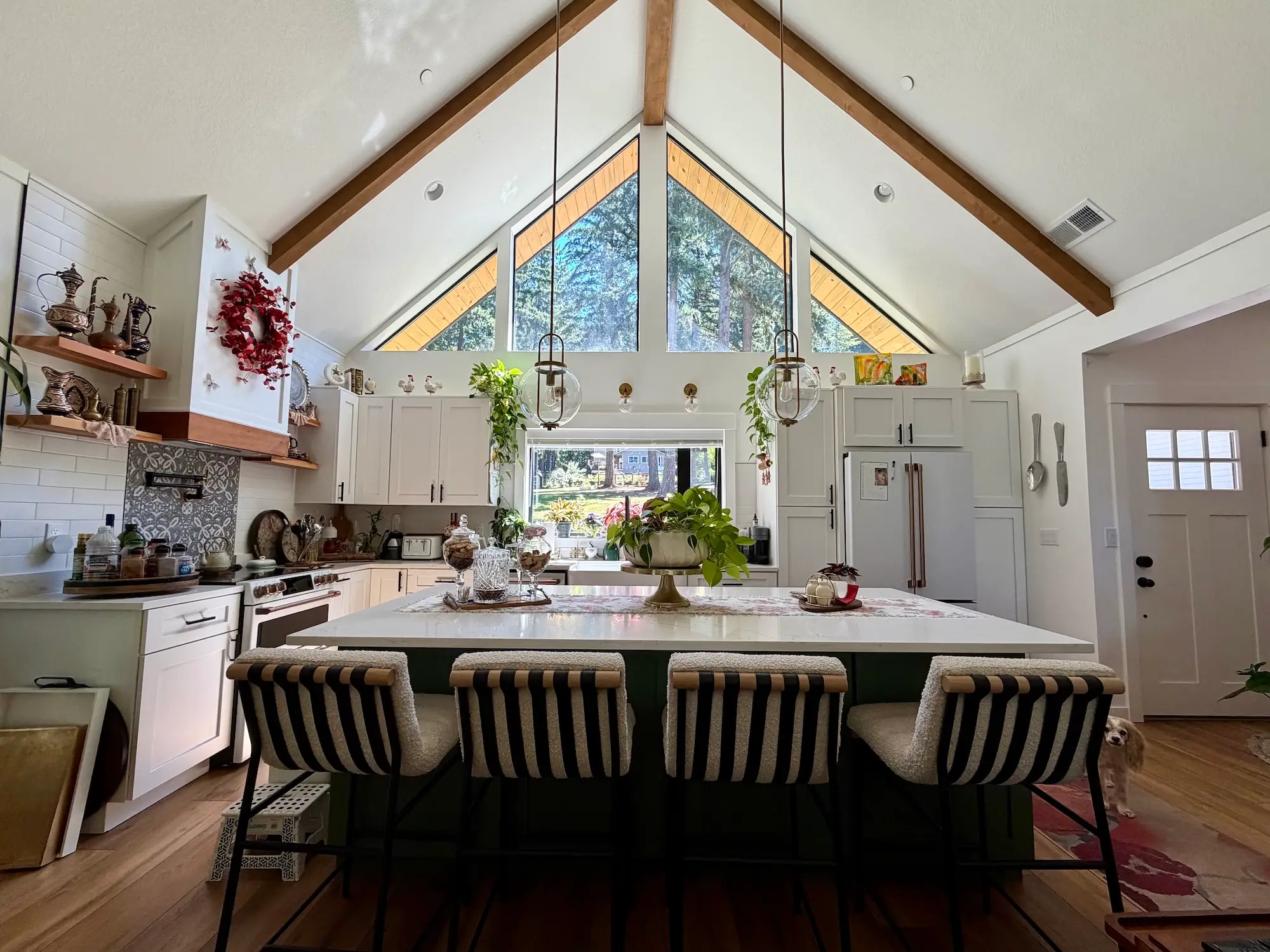 A kitchen with white walls, white cabinetry, a high ceiling, and a large island.
