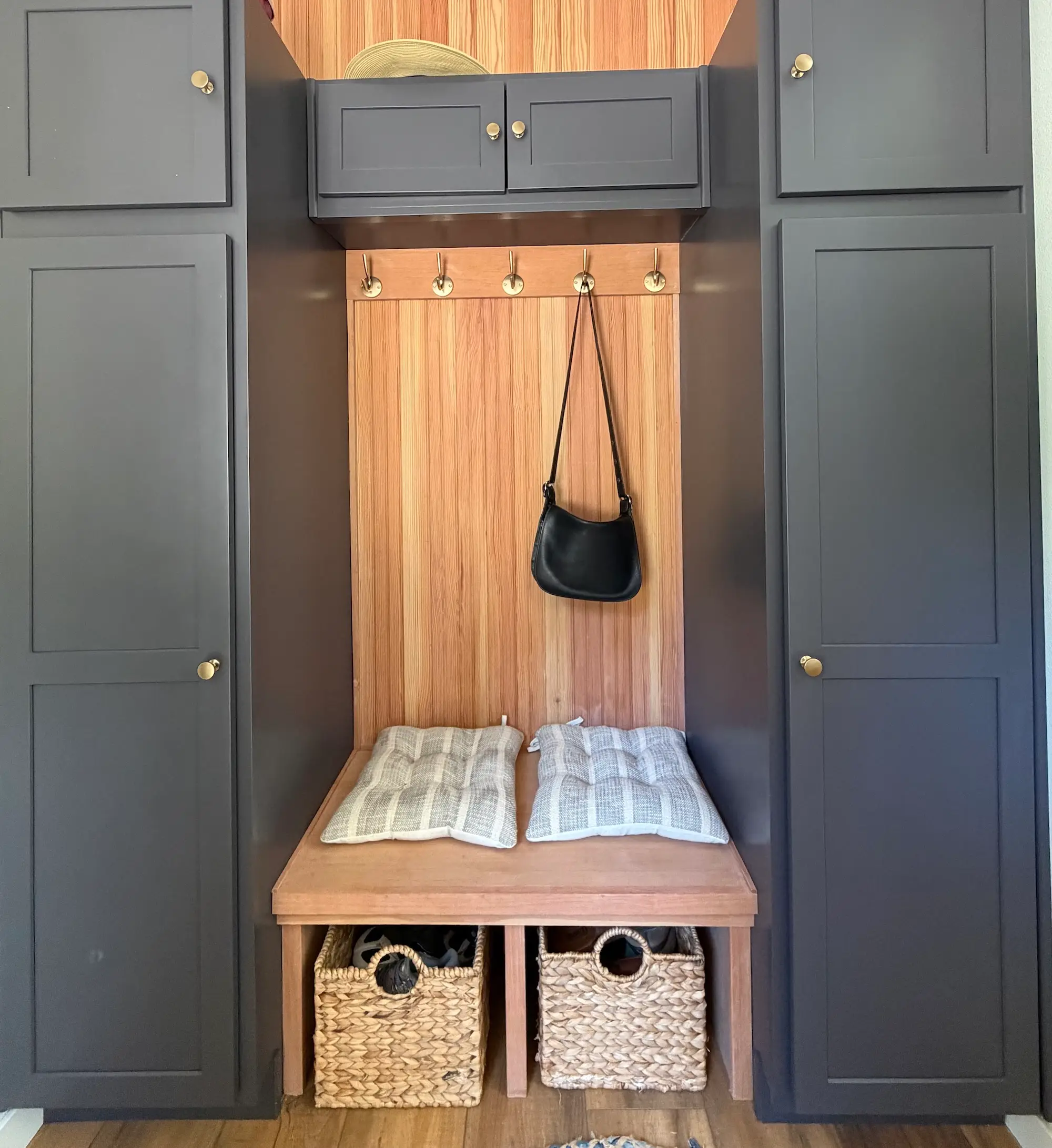A mudroom with gray cabinetry and a wooden bench.