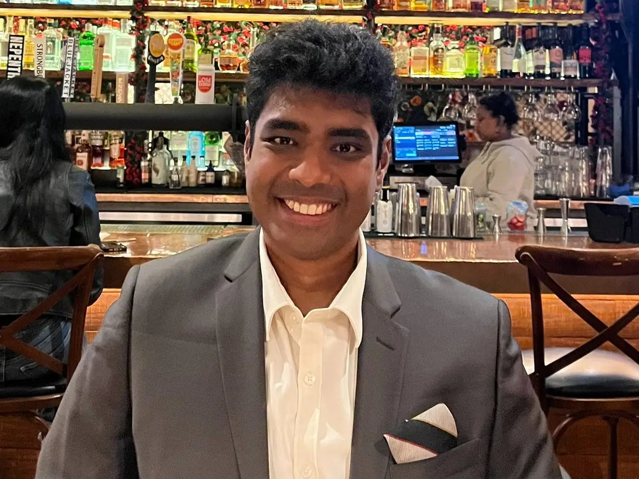 Mohamed Zeeshan is wearing a grey blazer with a white shirt.
