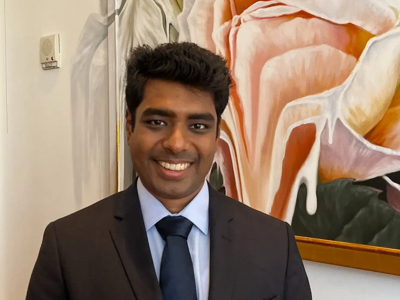 Mohamed Zeeshan is wearing a suit with a dark blue tie.
