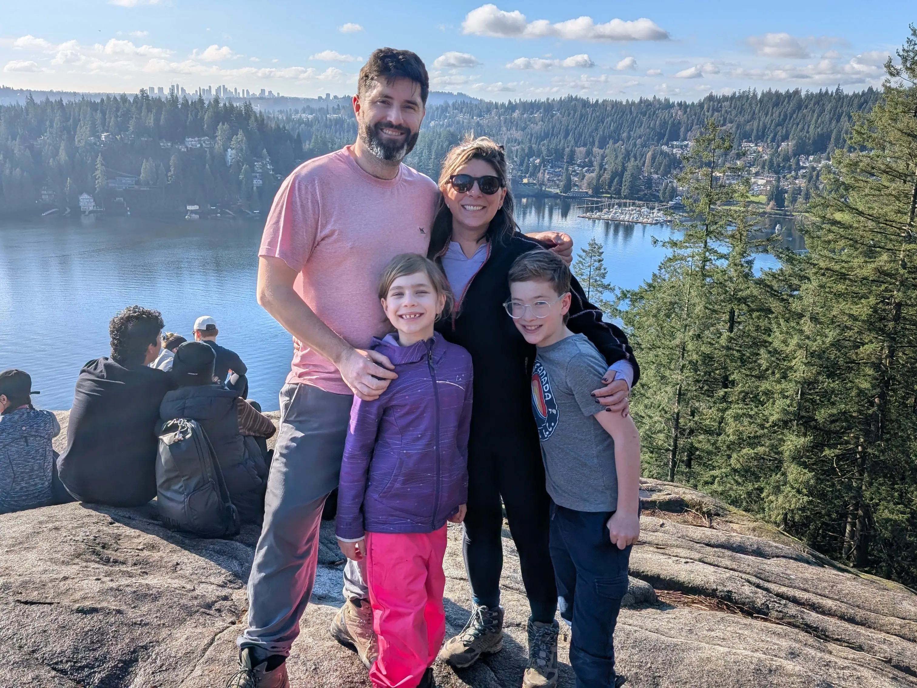 The family poses on a rock vista above a lake.
