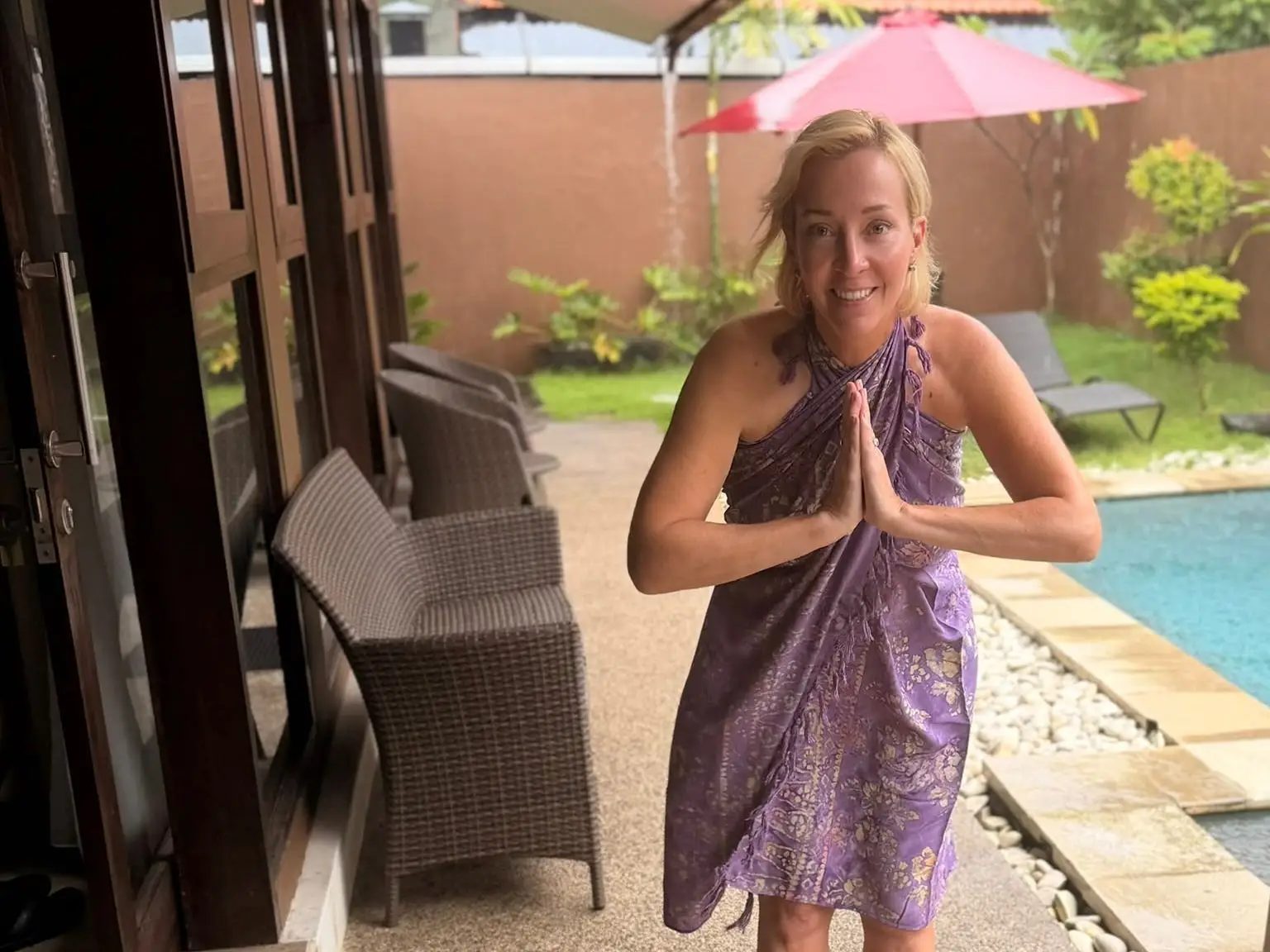 A woman wearing a sarong in Bali bowing by the pool.