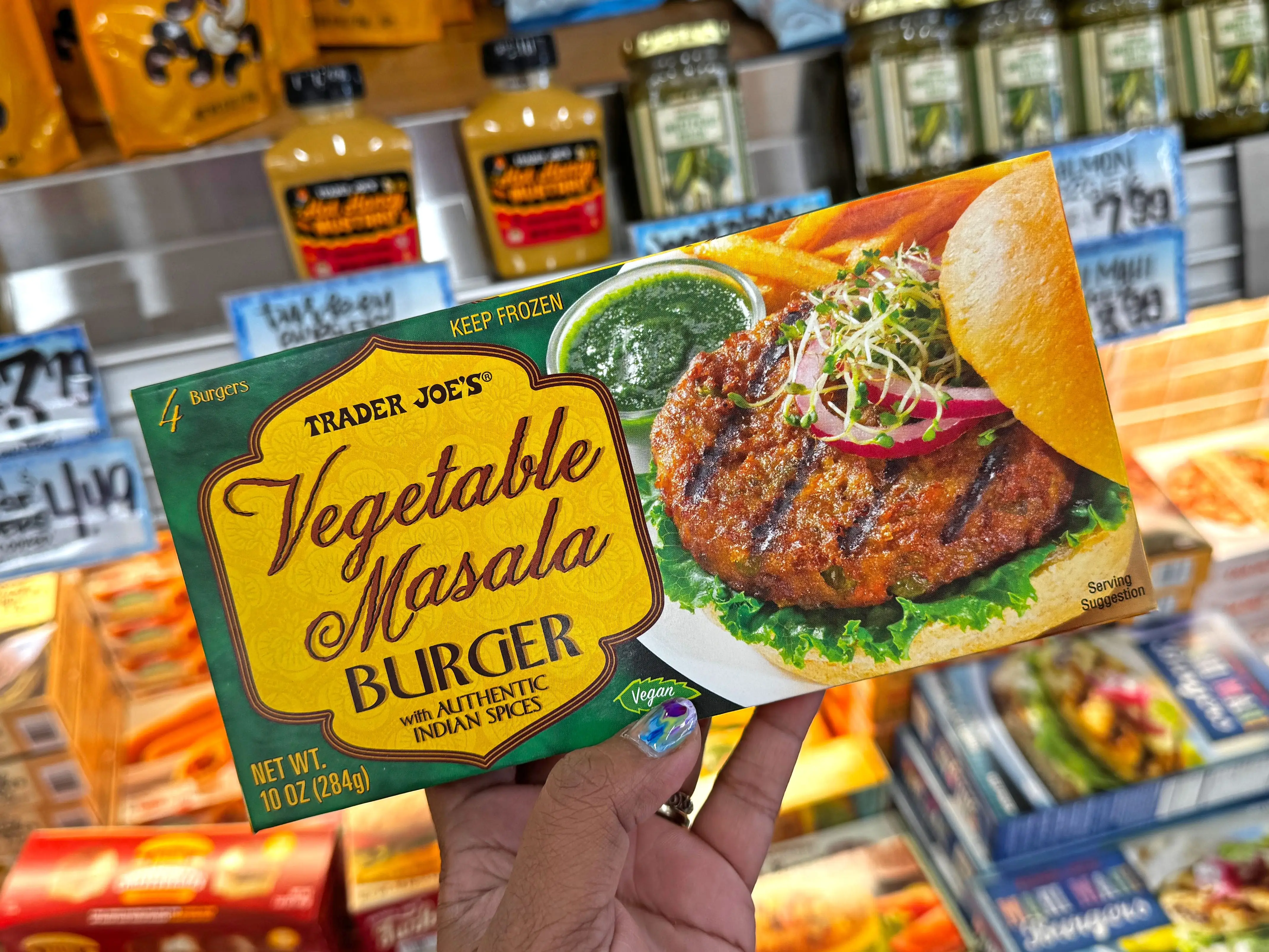 A hand holding a box of Trader Joe's vegetable masala burgers.