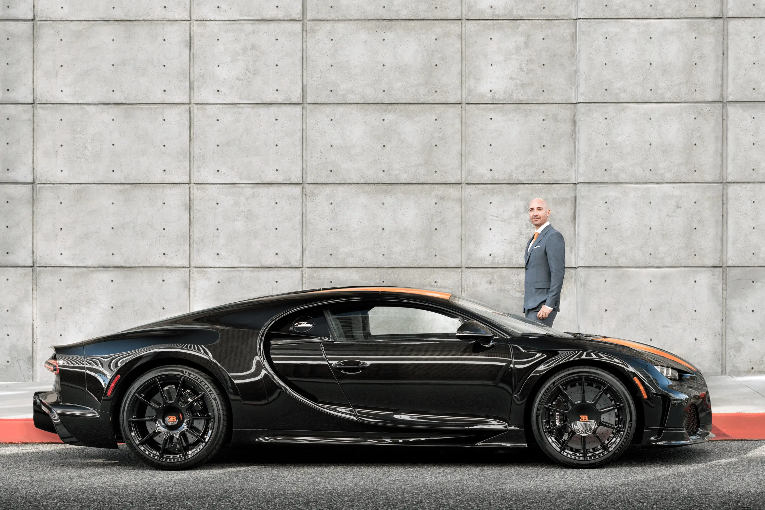Sascha Doering stands next to a black Bugatti.