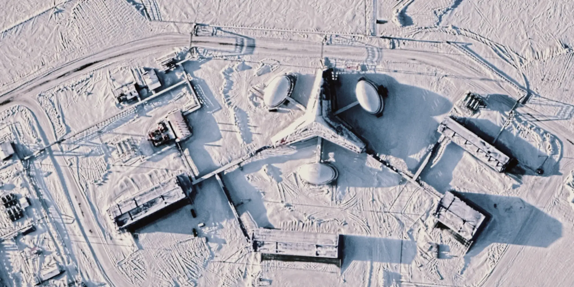 A satellite image of a snow-covered landscape with a trefoil shaped building