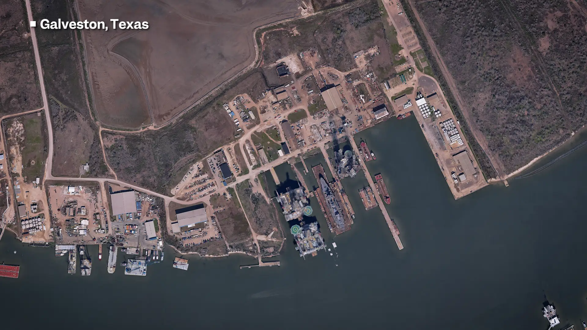 A satellite image labelled Galveston, Texas of a small port with a few docks and around five ships of various sizes.