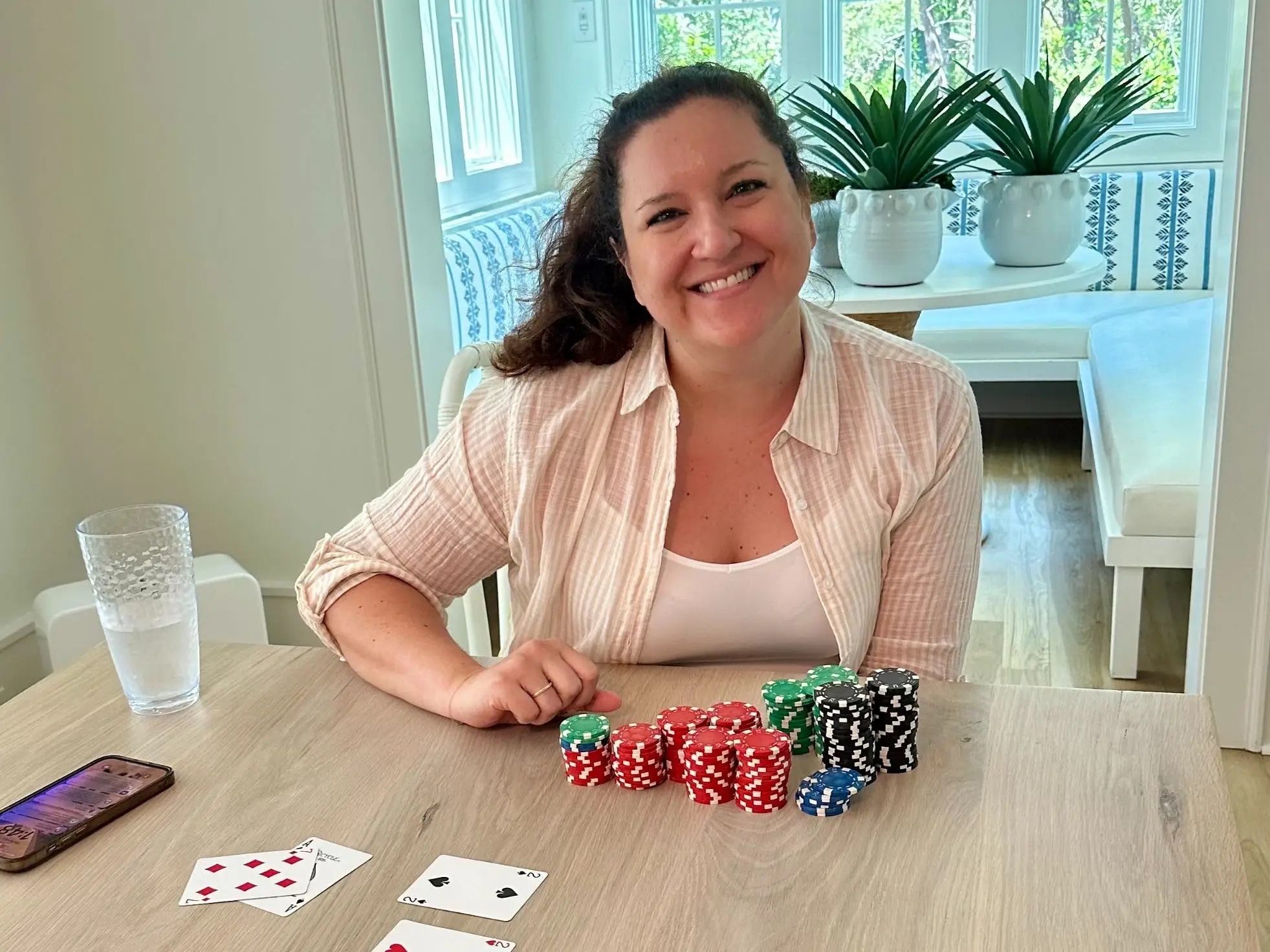 The writer sitting at a table with a variety of poker chips and playing cards.