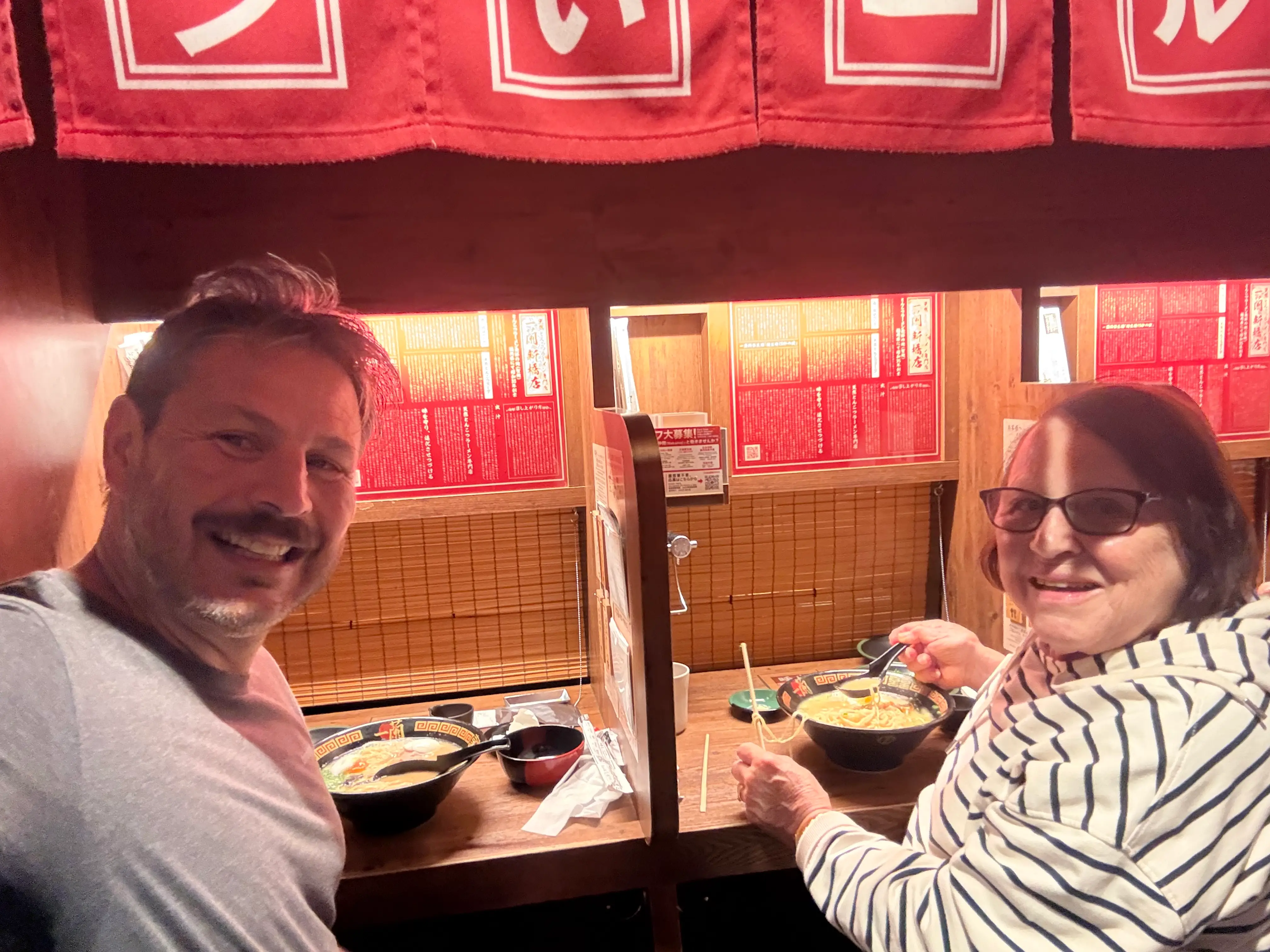 Author Ash Jurberg and his mom smiling at ramen restaurant