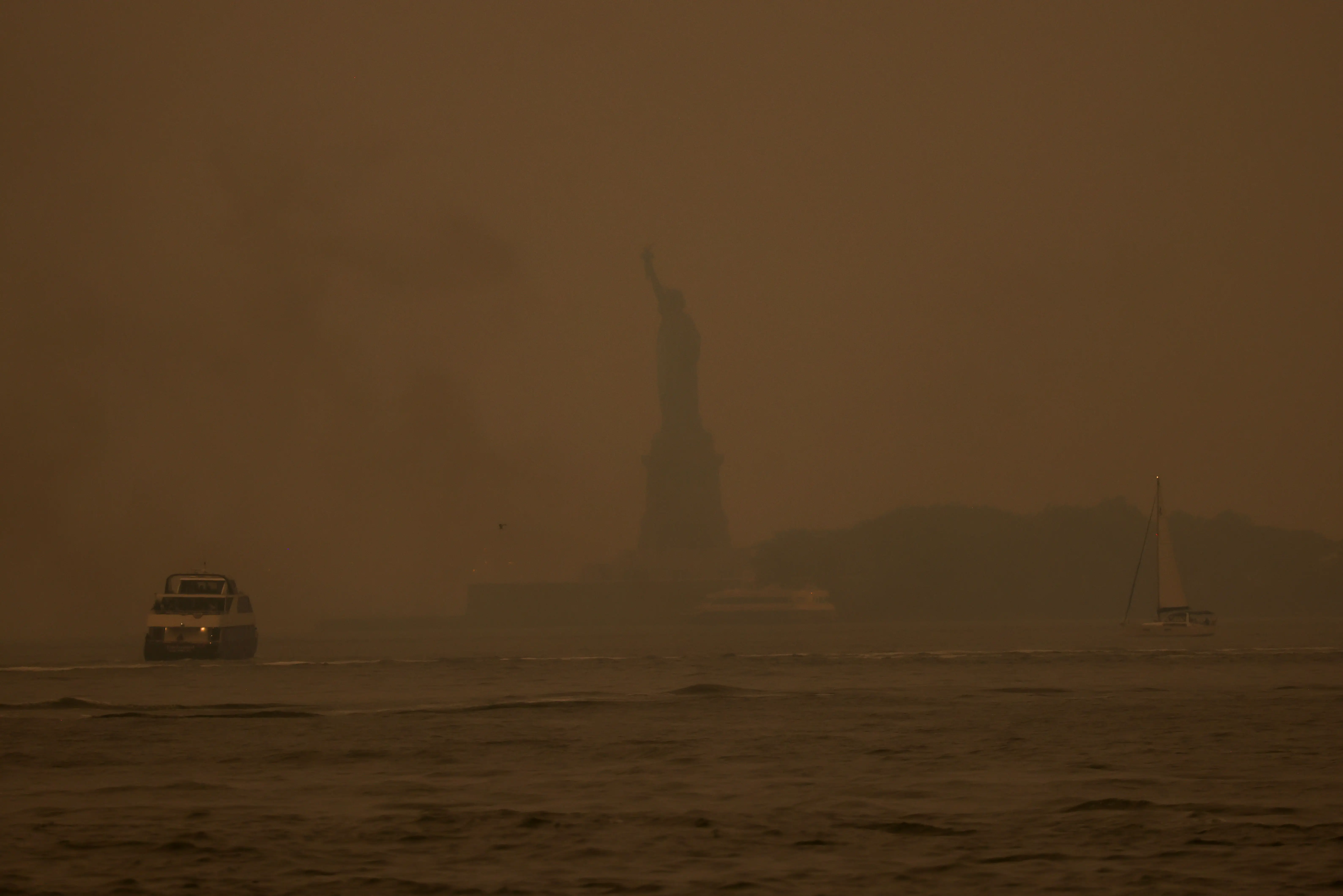 The Statue of Liberty obscured by yellow wildfire smoke.