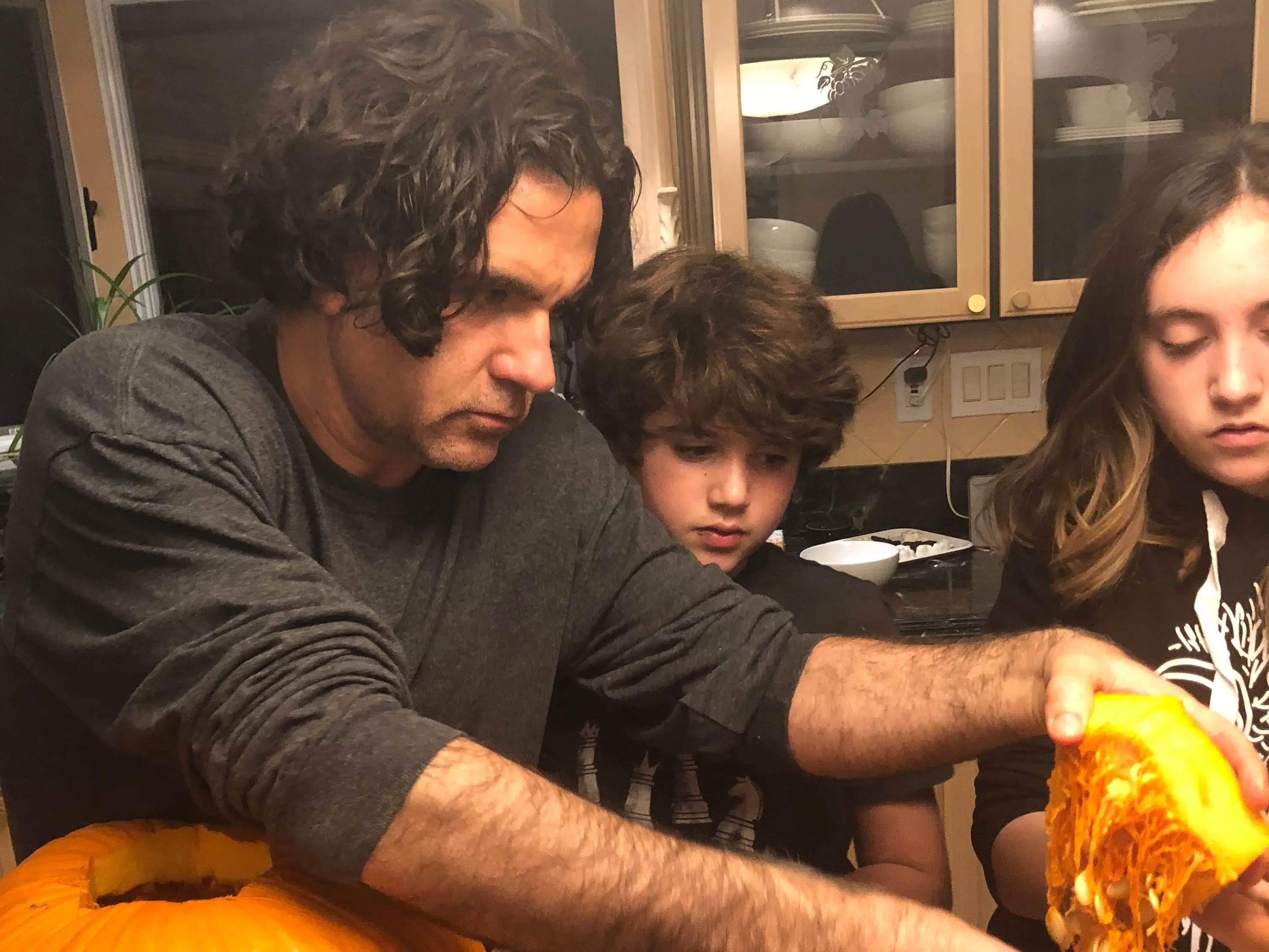 Man helping kids remove guts from a pumpkin