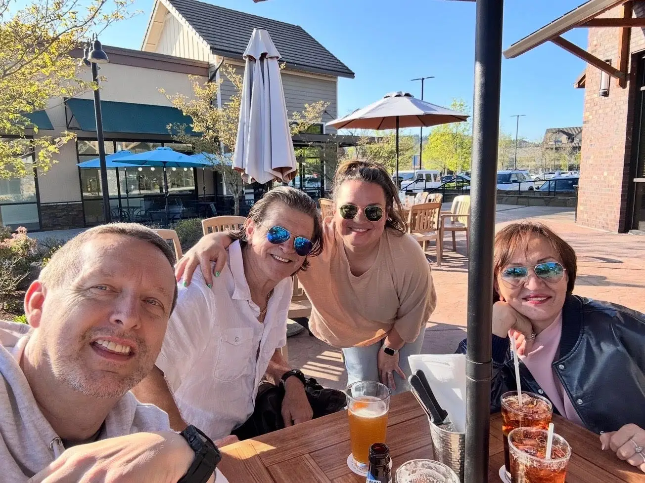A selfie of a family of four at a table on a patio.