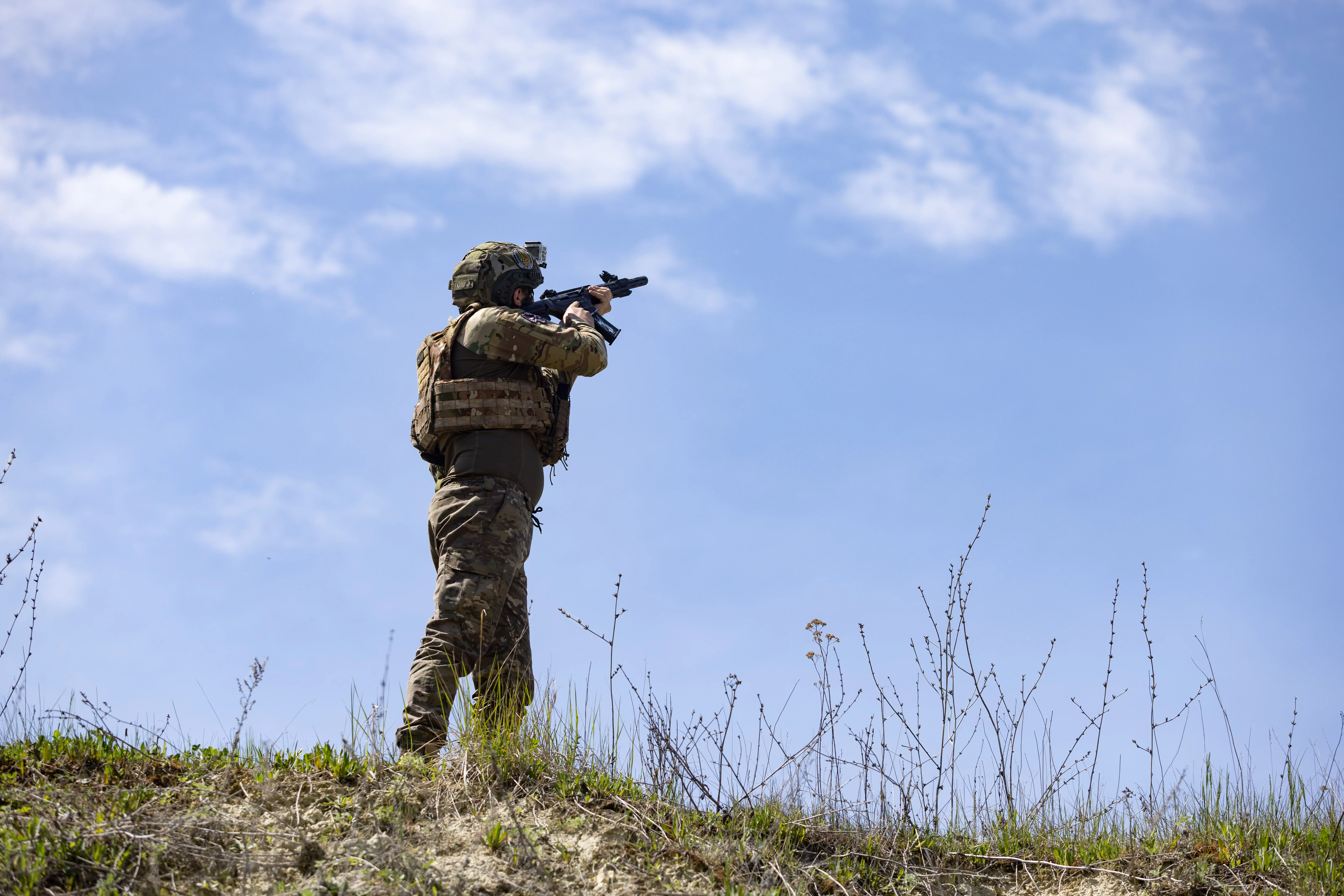 A serviceman of the 22nd Separate Mechanized Brigade aims an automatic rifle skyward on May 9, 2026 in Kharkiv, Ukraine.