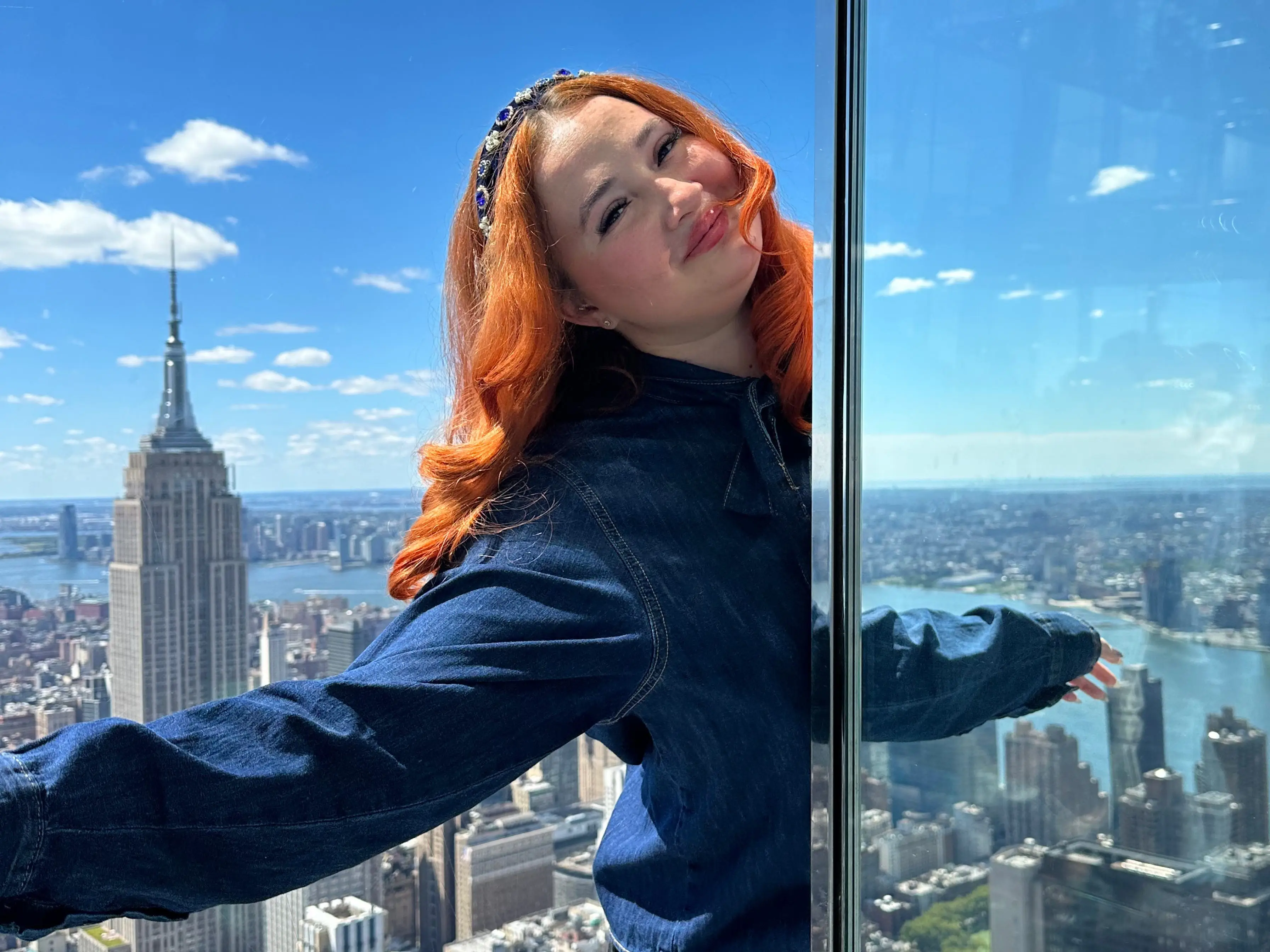 Annmarie stretches her arms out at an overlook by the Empire State Building.