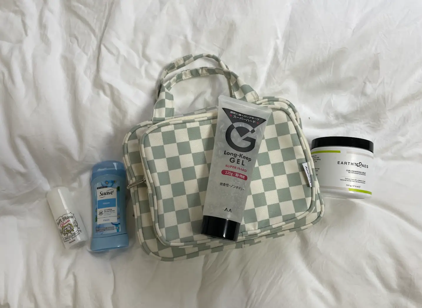 Gel, deodorant, and other toiletries on a white bedspread.