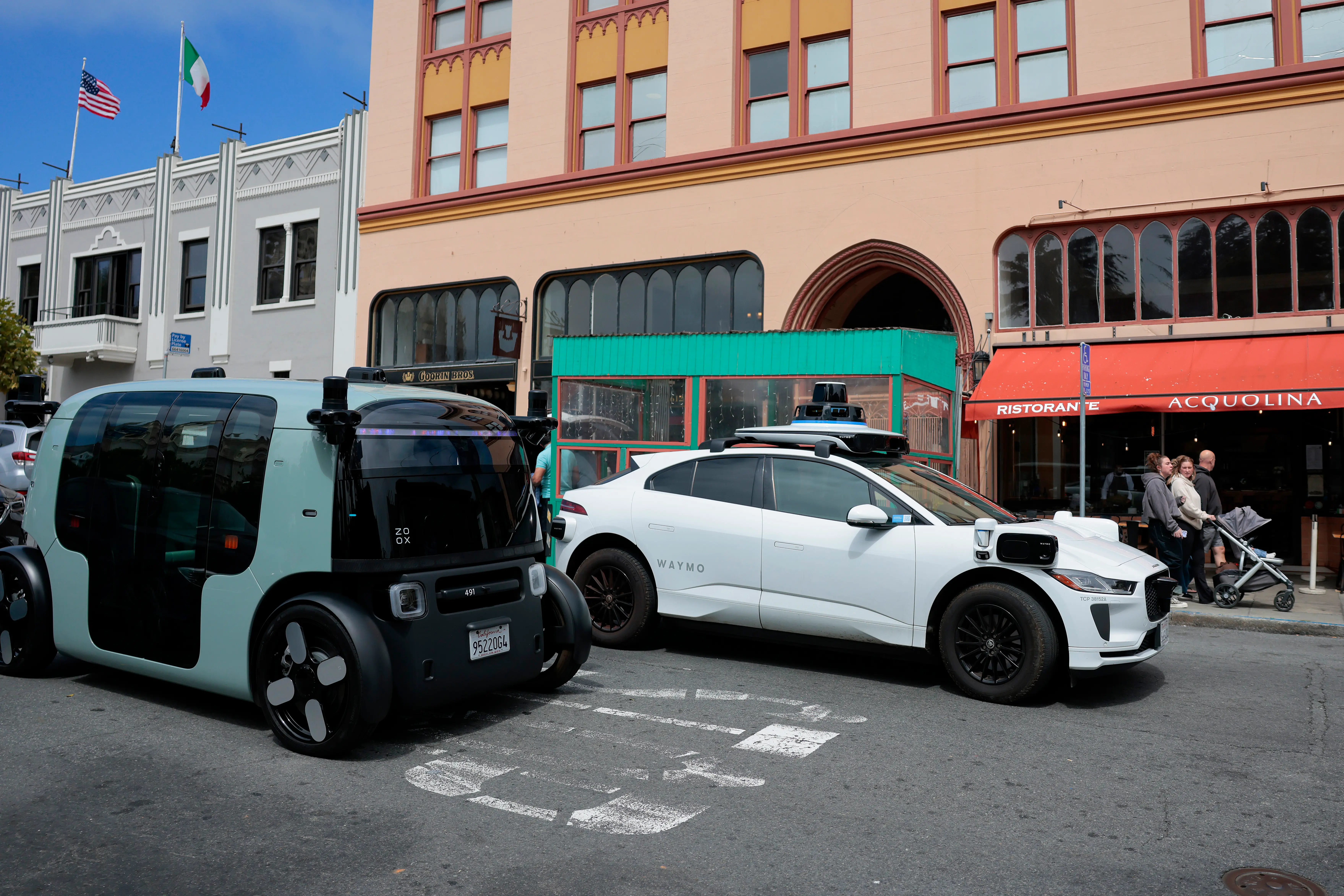 A Waymo robotaxi passes a Zoox robotaxi on the road in North Beach on July 07, 2026 in San Francisco, California. Several Waymo vehicles were towed after the company said their batteries died while they were stuck in heavy traffic during Fourth of July celebrations in San Francisco.