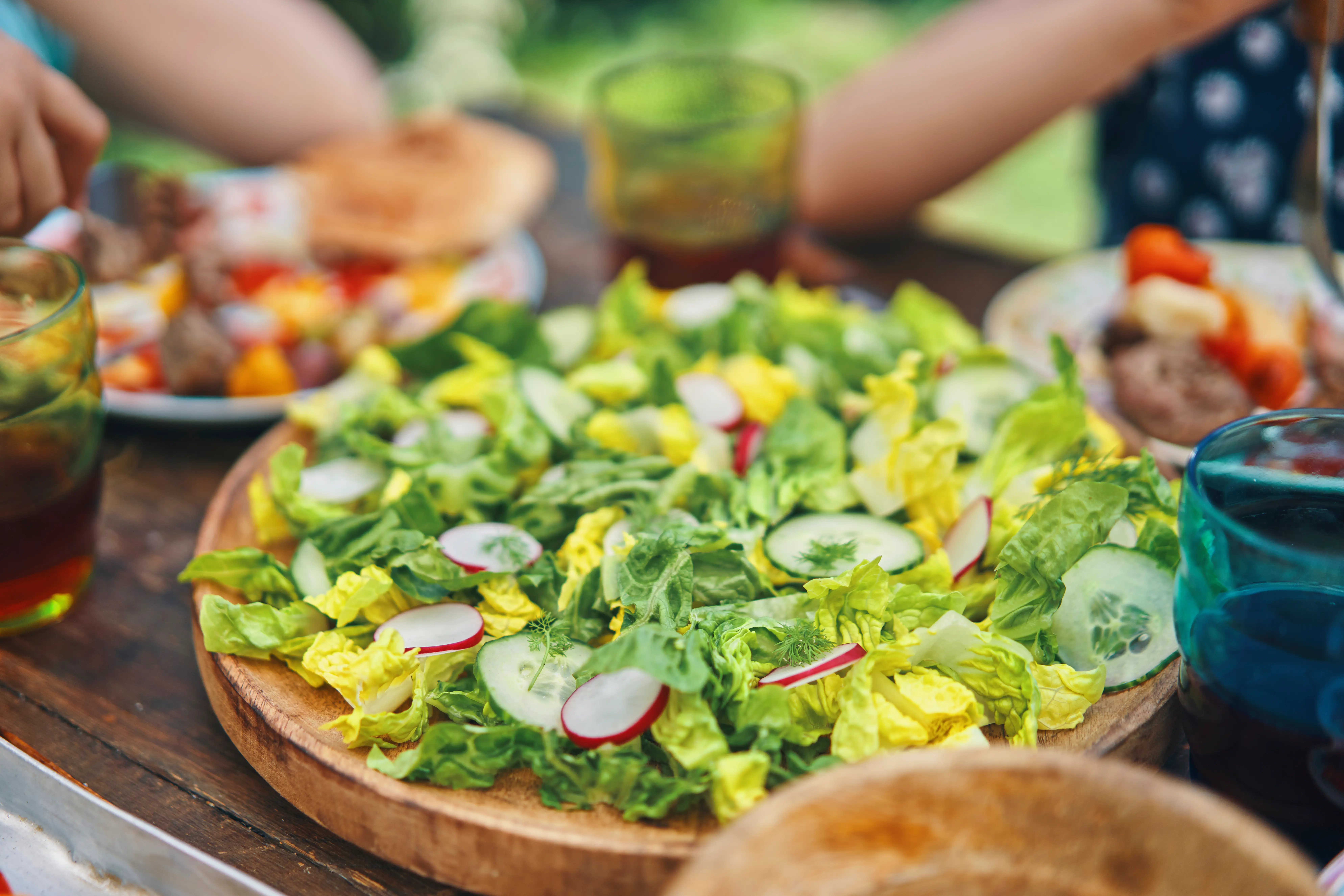 A salad is shown while people are eating outside.