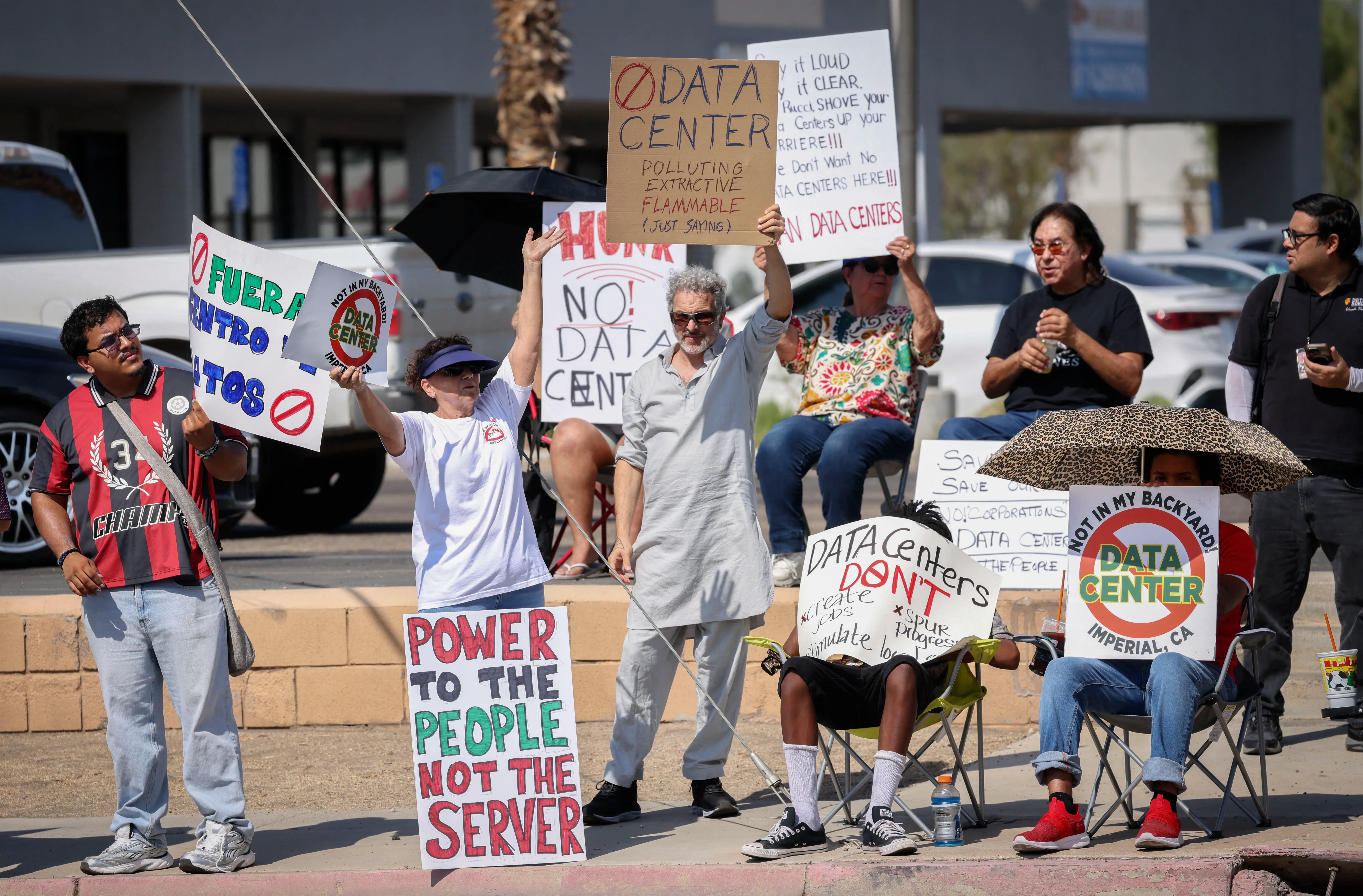 Protesters wave signs protesting AI data centers