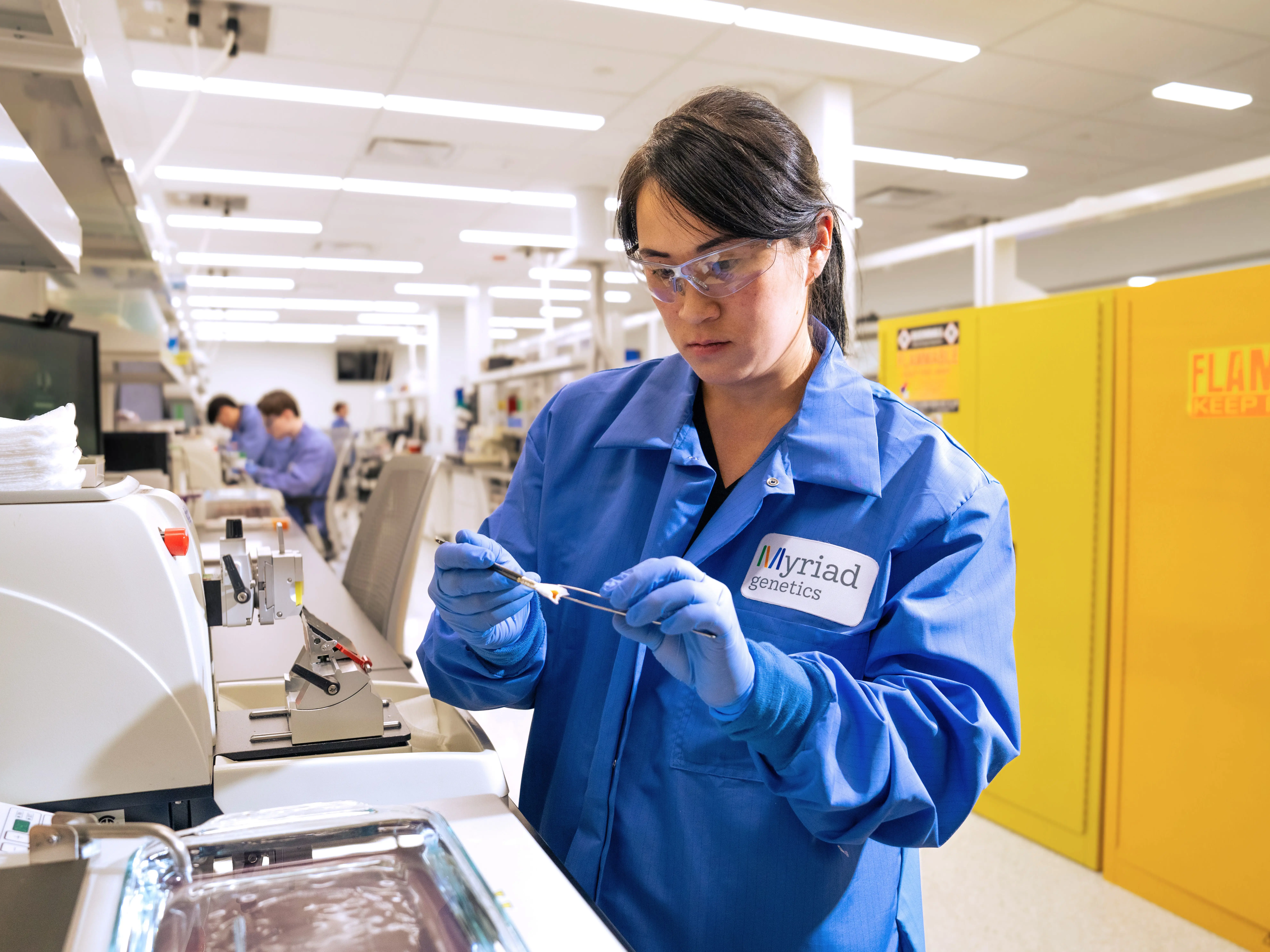 A myriad of Genetics laboratory worker in safety glasses and a blue coat handling a sample.