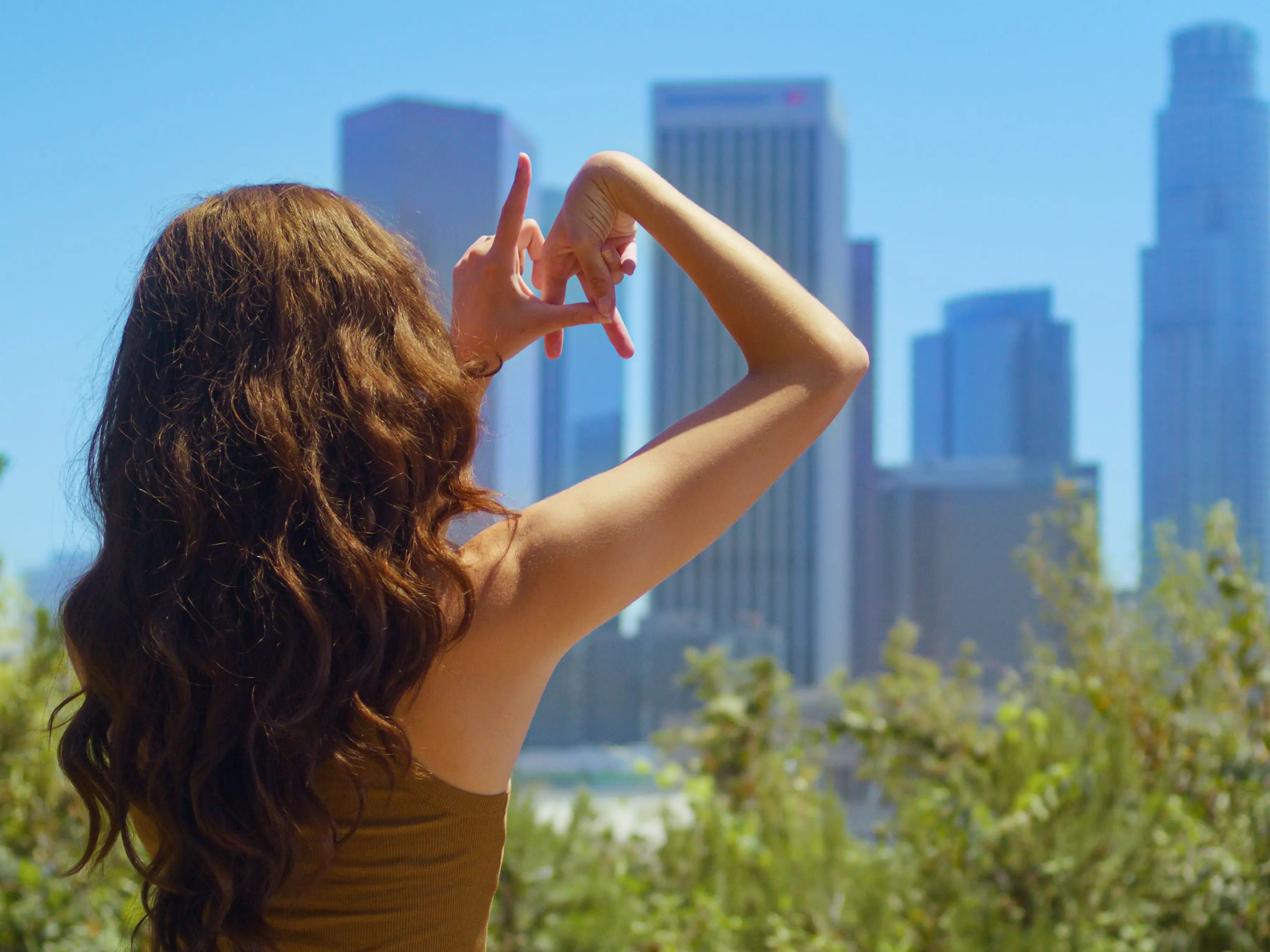 girl fingers make sign LA on cityscape view