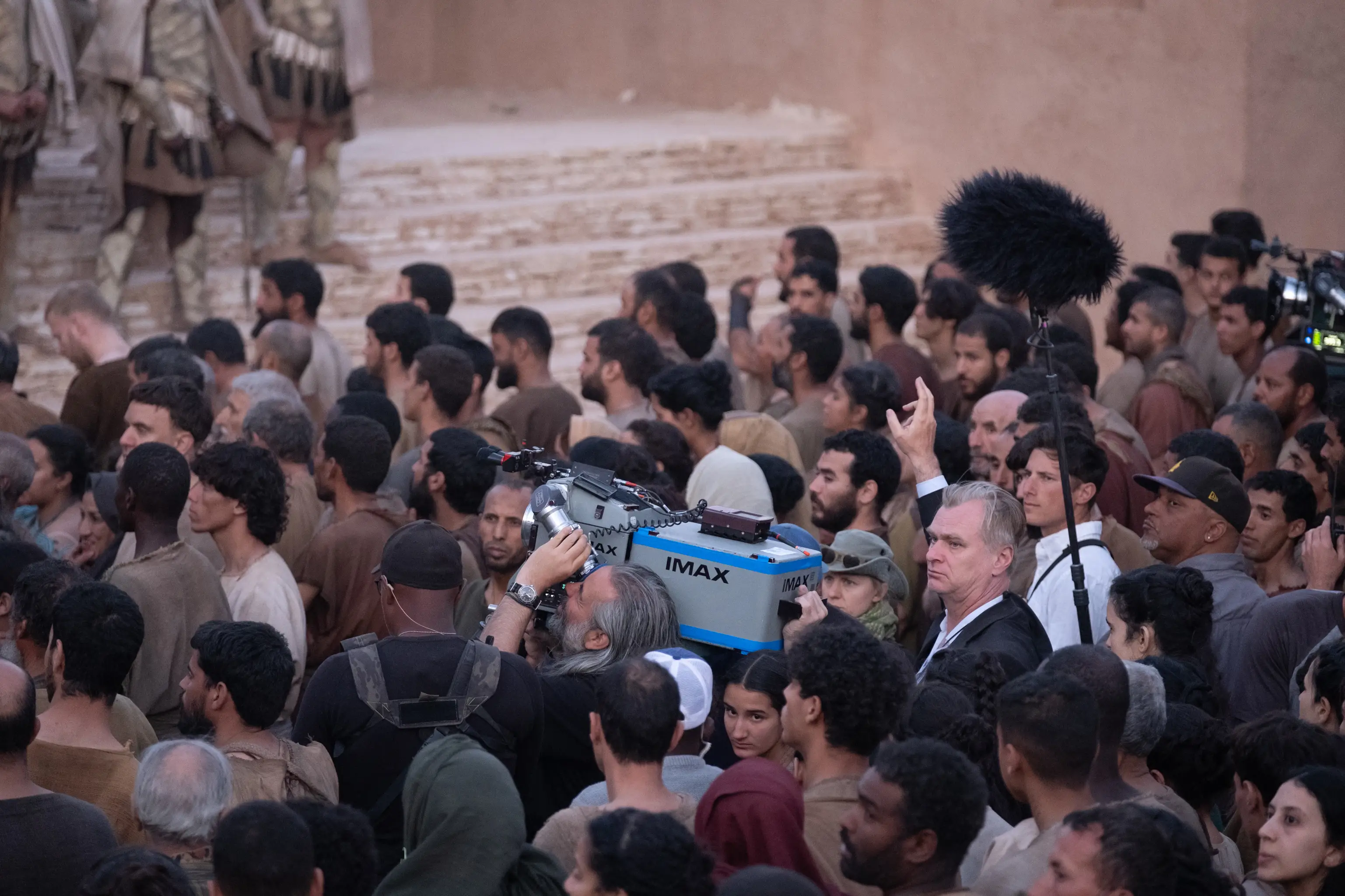 Christopher Nolan surrounded by extras on set of The Odyssey