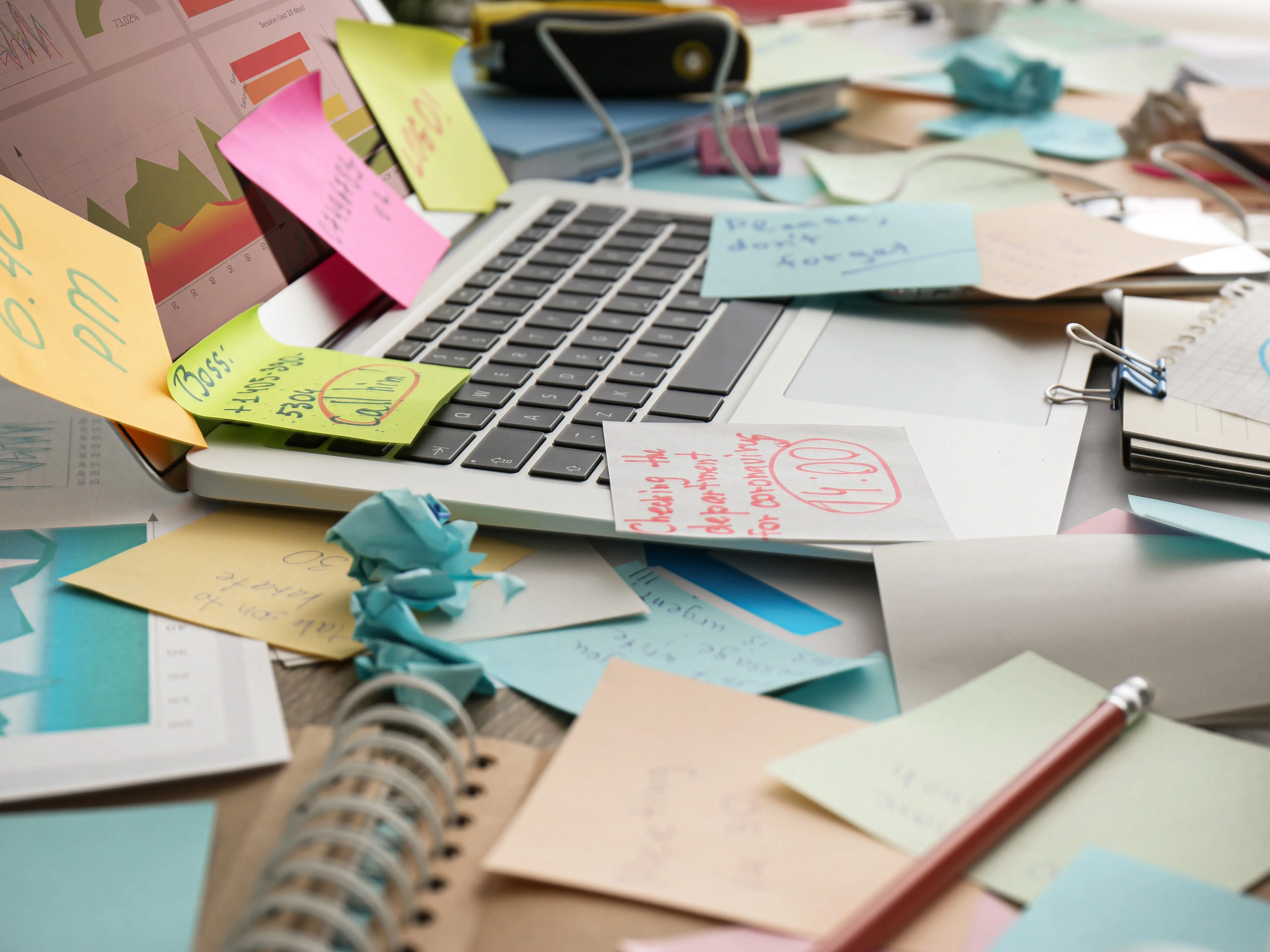 Laptop littered with sticky notes and papers