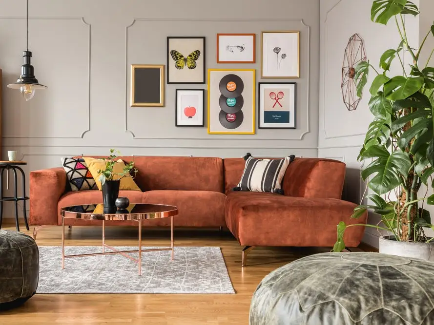 brown sectional couch with gallery wall above and plants