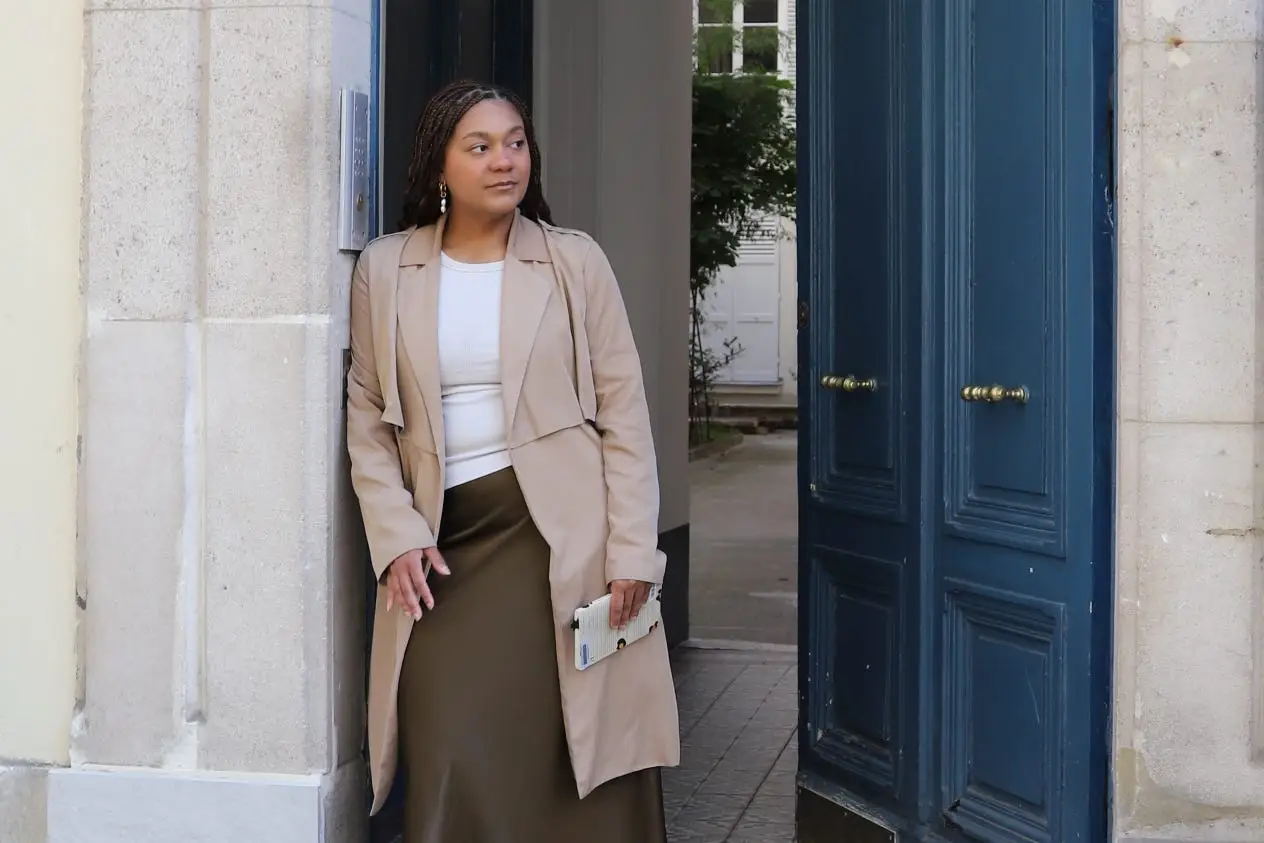 Author Naydeline Mejia leaning on doorway next to blue door, looking to the side