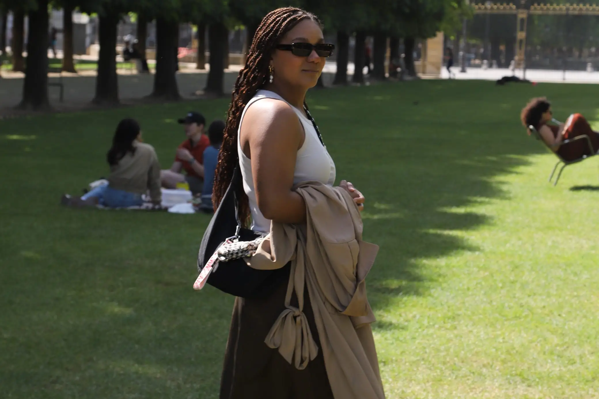 Author Naydeline Mejia in park holding jacket over her arm, wearing sunglasses