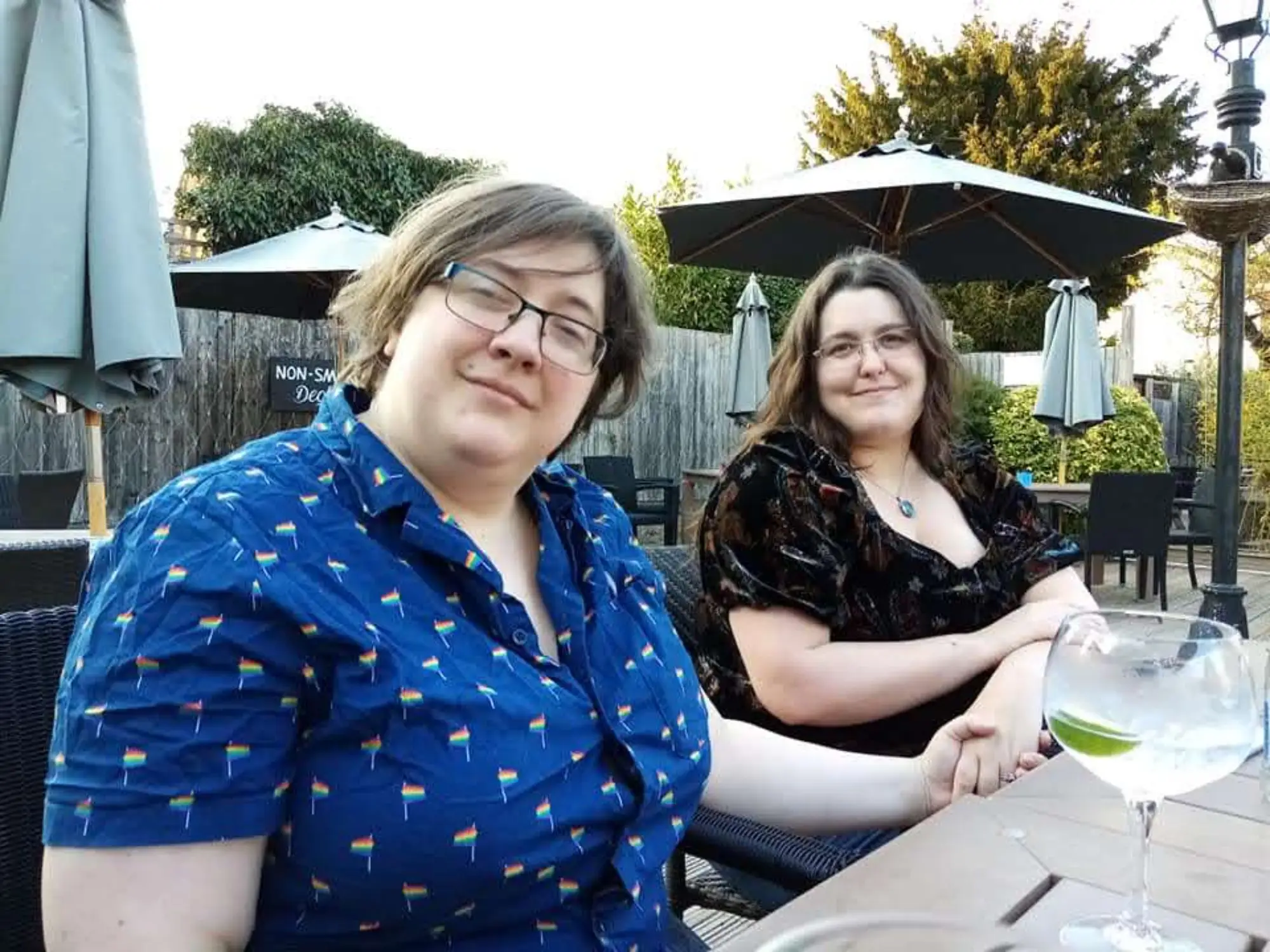 The writer and her wife sitting at an outdoor table holding hands.