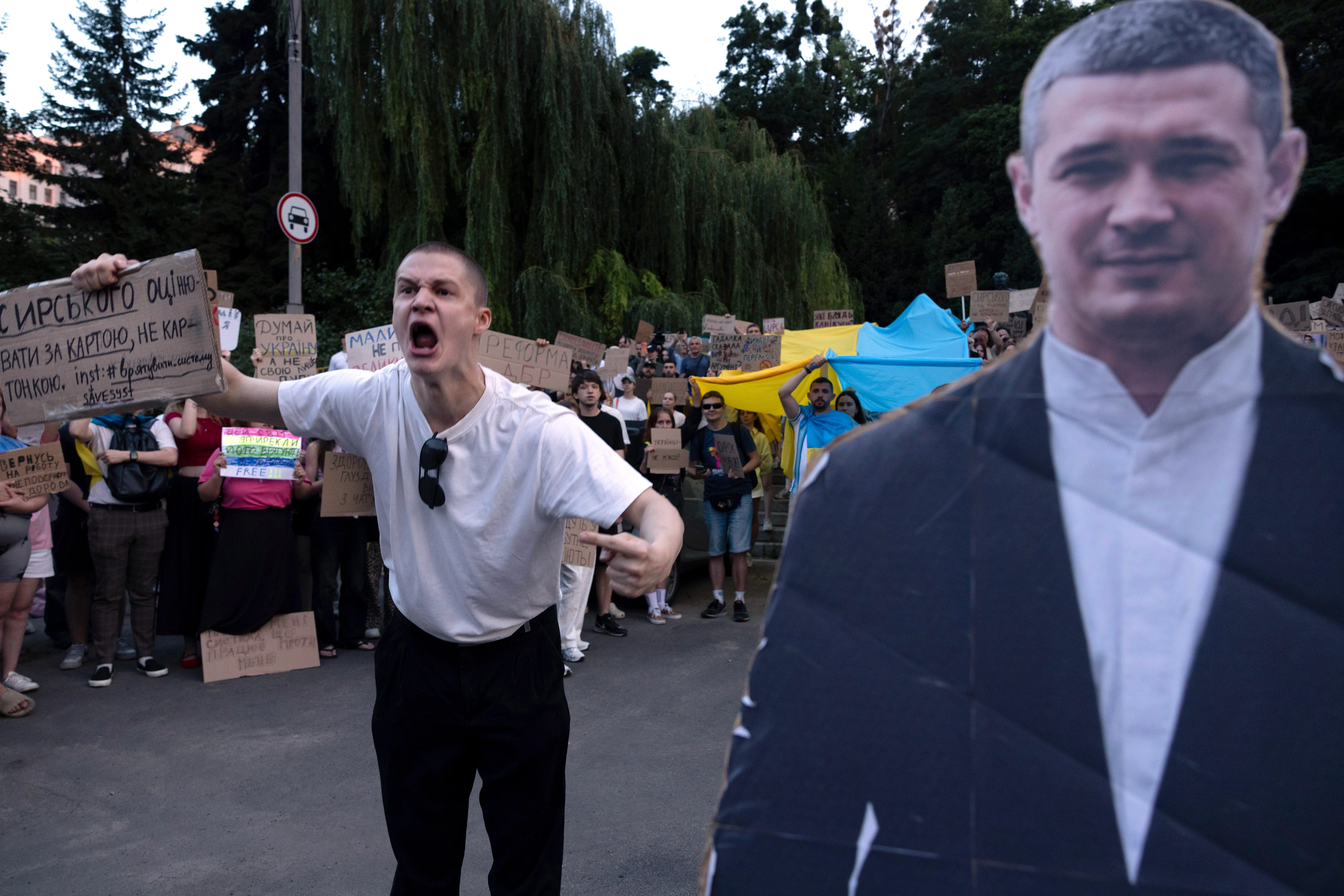A man holds up a sign and yells in protest next to a cutout of Fedorov.