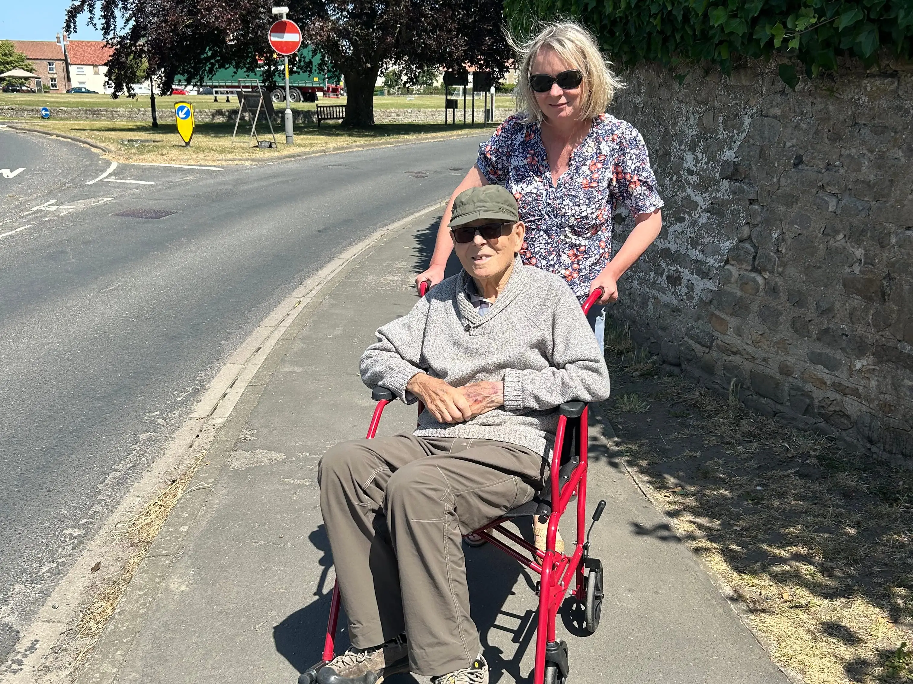 A woman pushing an older man in a wheelchair.