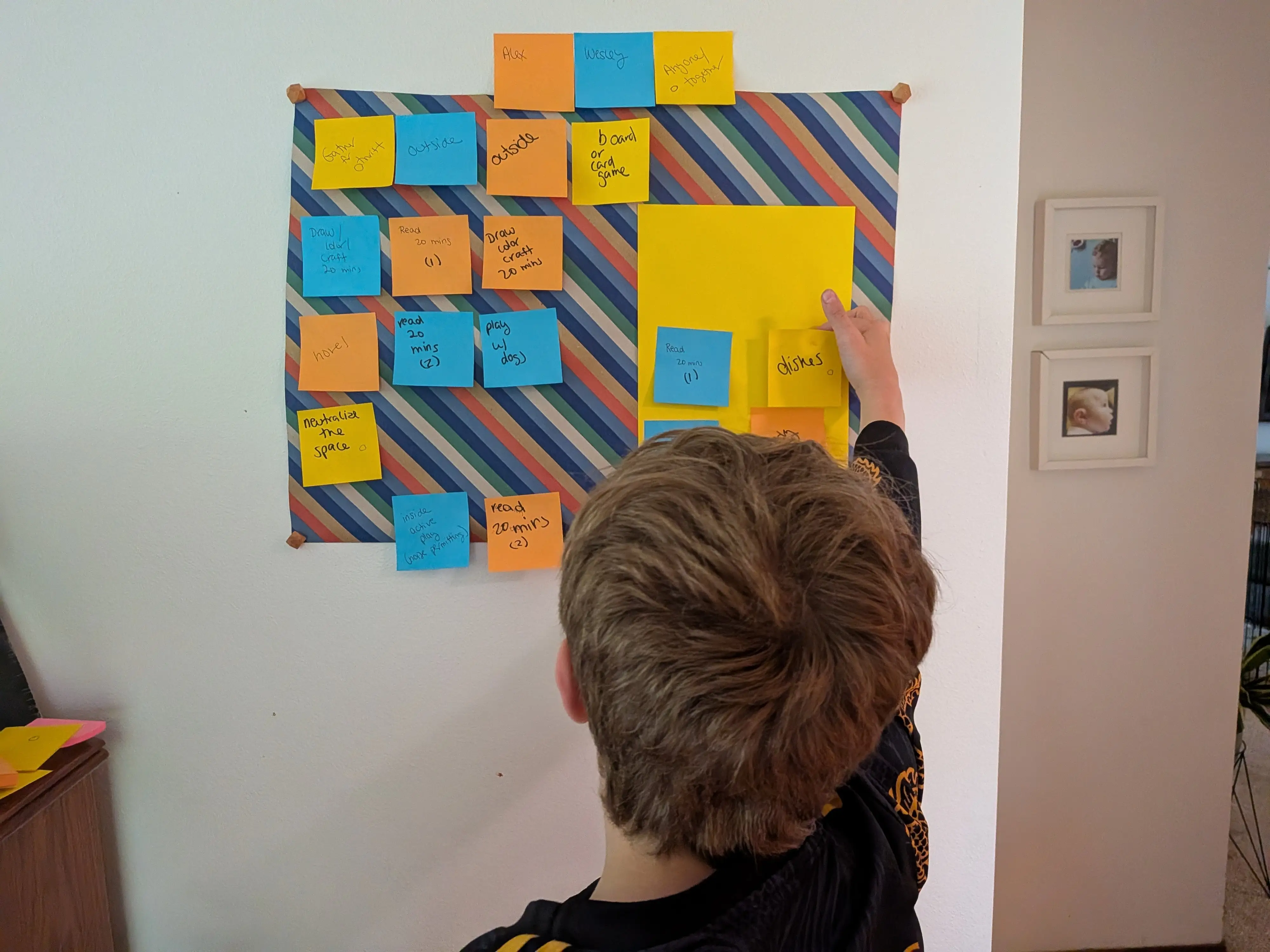 A boy moves a sticky note that his family is using to help organize thier summer activities.