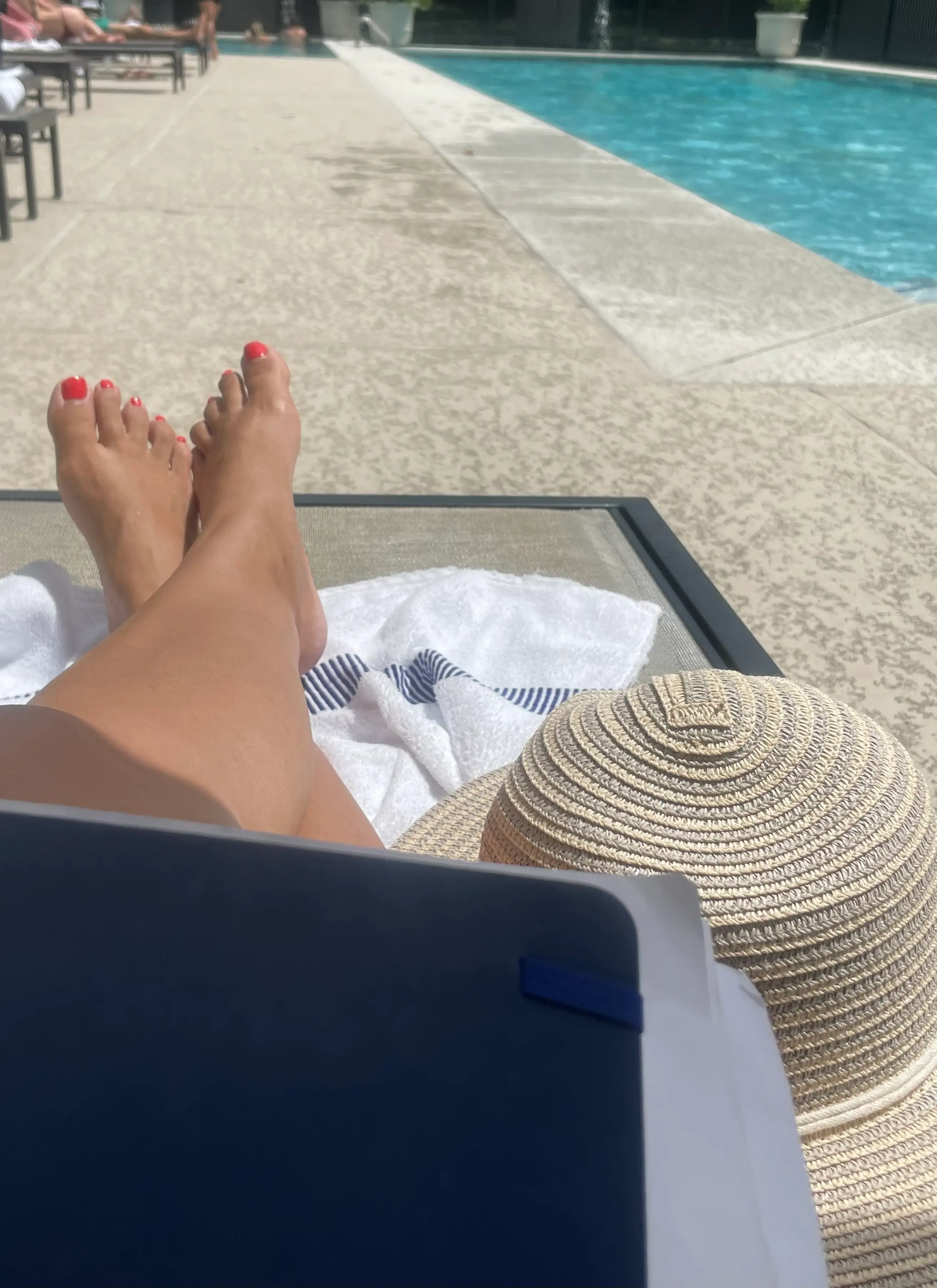 A woman works on a laptop near a pool.