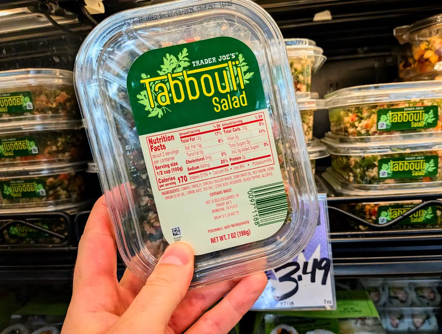 The writer holding a container of Trader Joe's tabbouli salad.