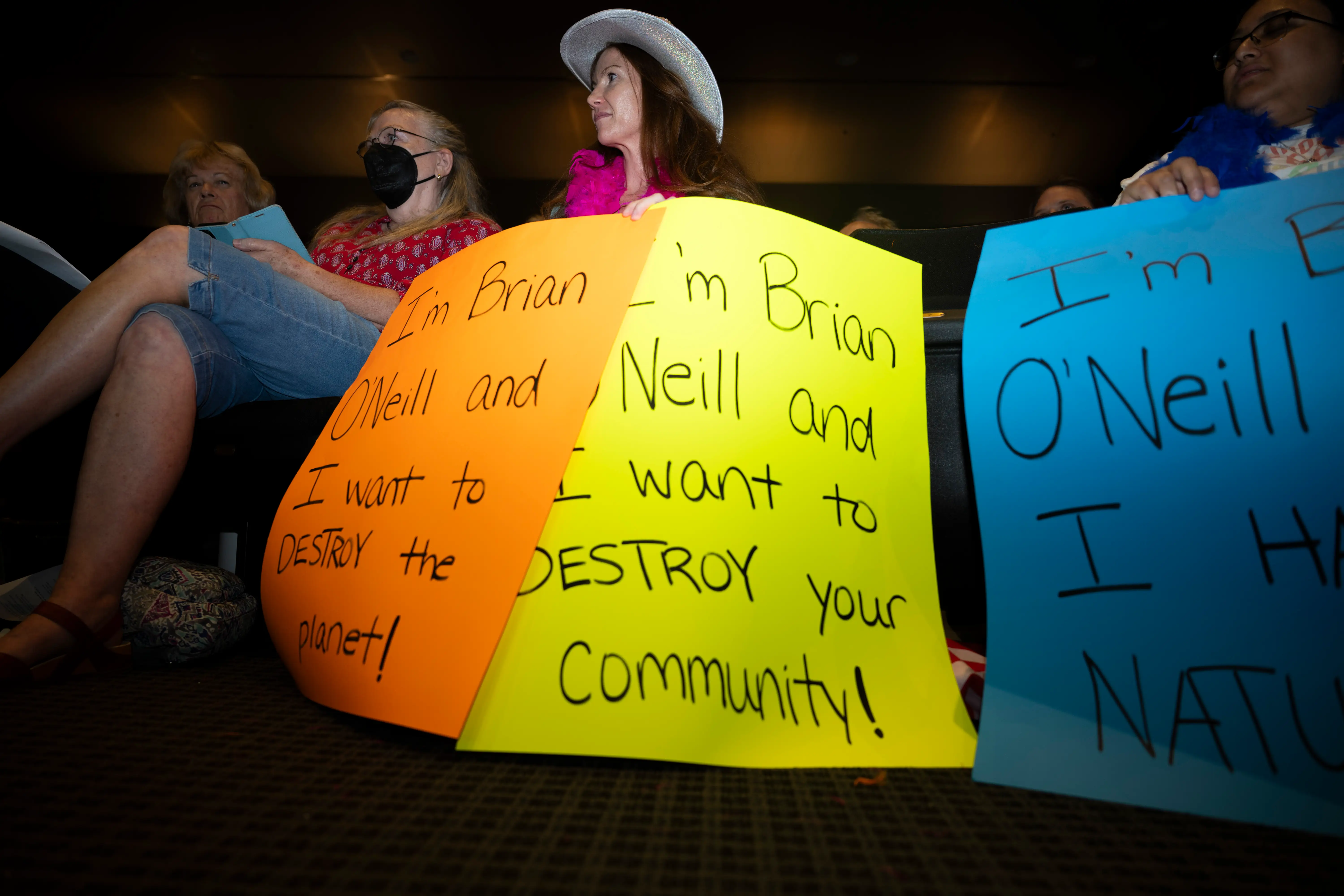 Residents hold signs directed at the developer behind the AI data center project
