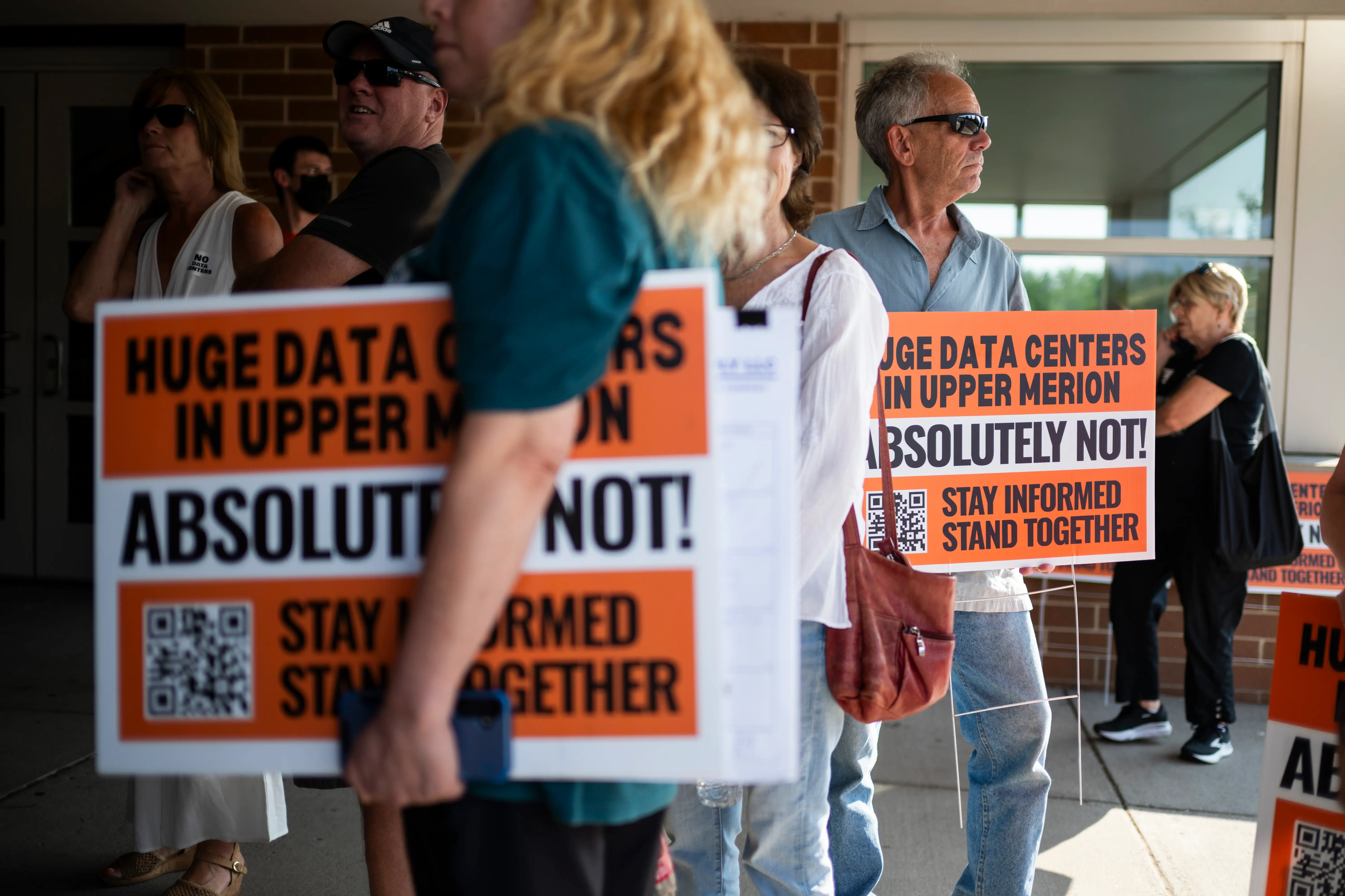 Residents carry signs opposing an AI data center in Upper Merion Township, Pennsylvania