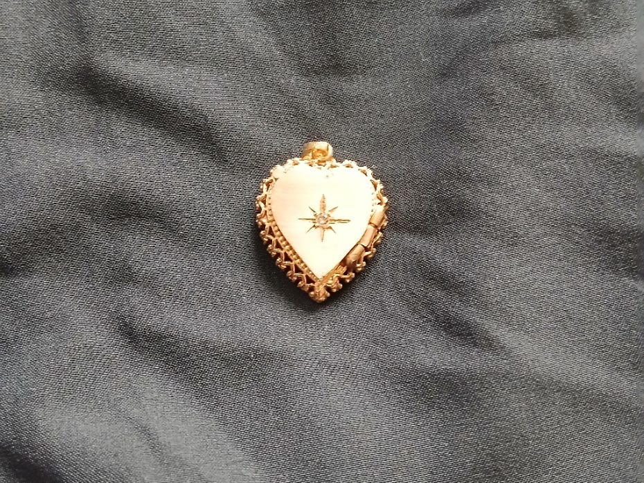 A gold locket on a gray background.