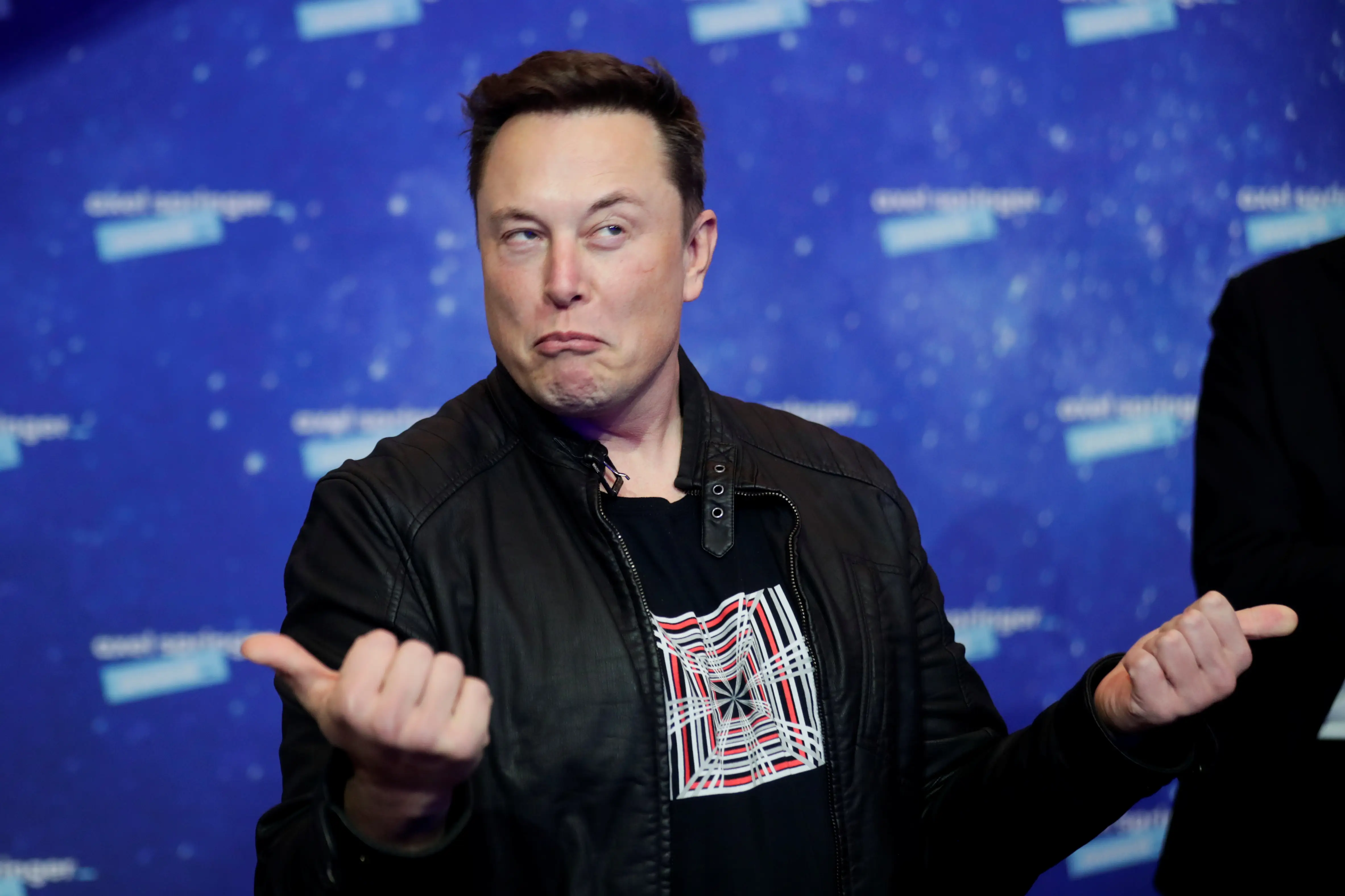 Elon Musk scrunches his face and twists his arms onstage.