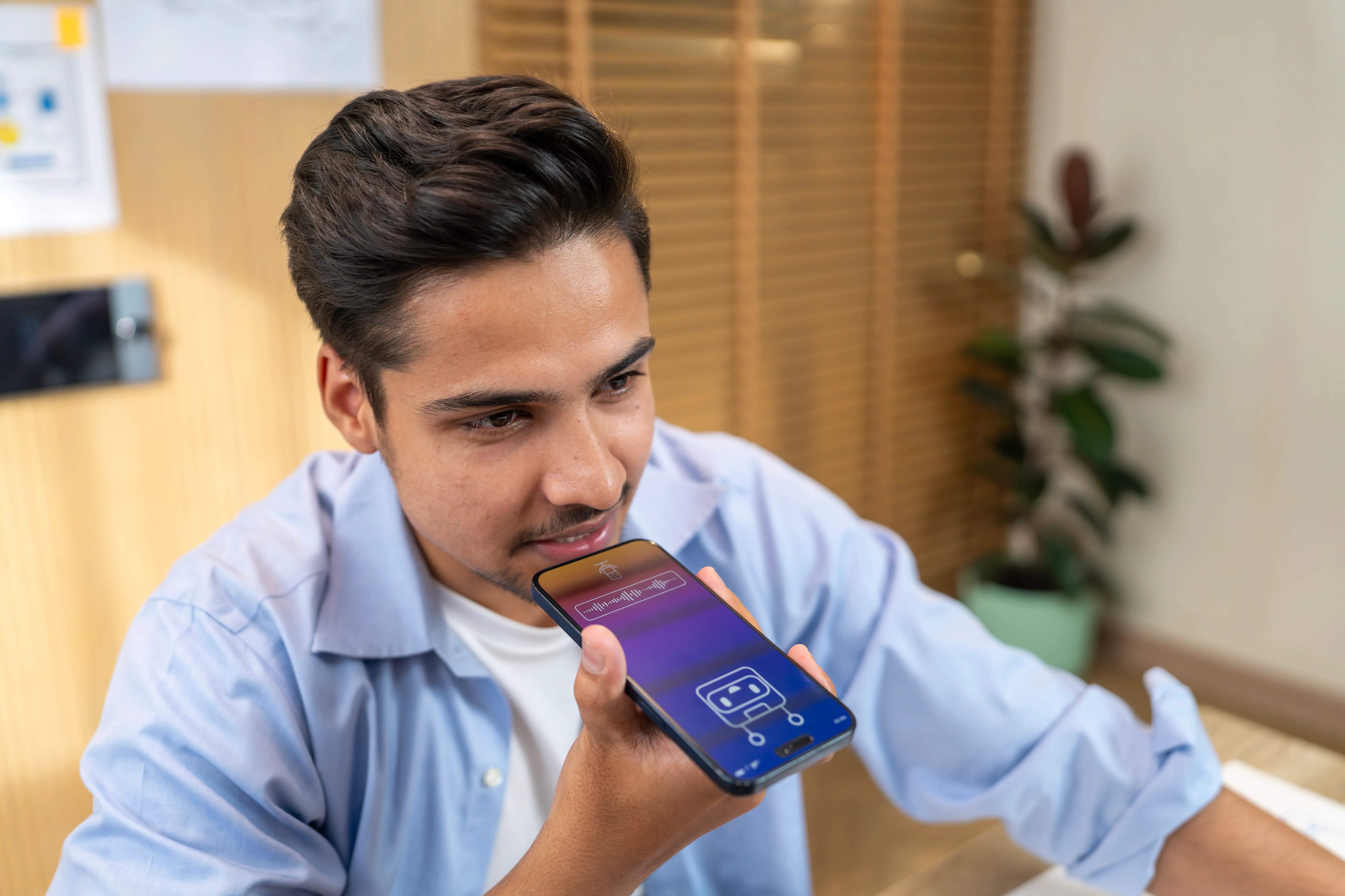 A person in a blue shirt speaks into their phone.