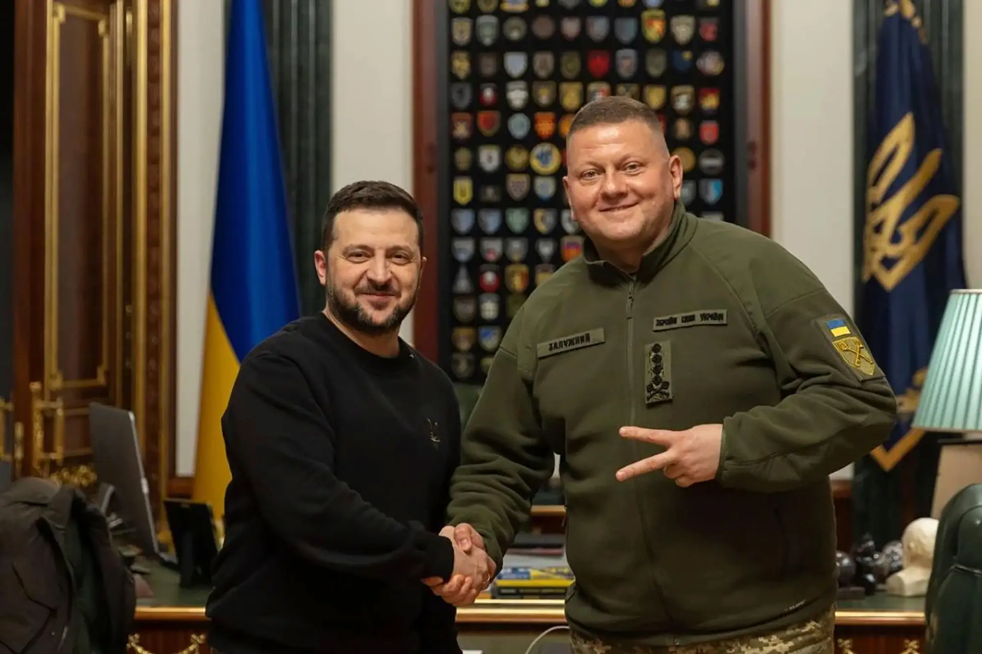 Zelenskyy and Zaluzhnyi shake hands.