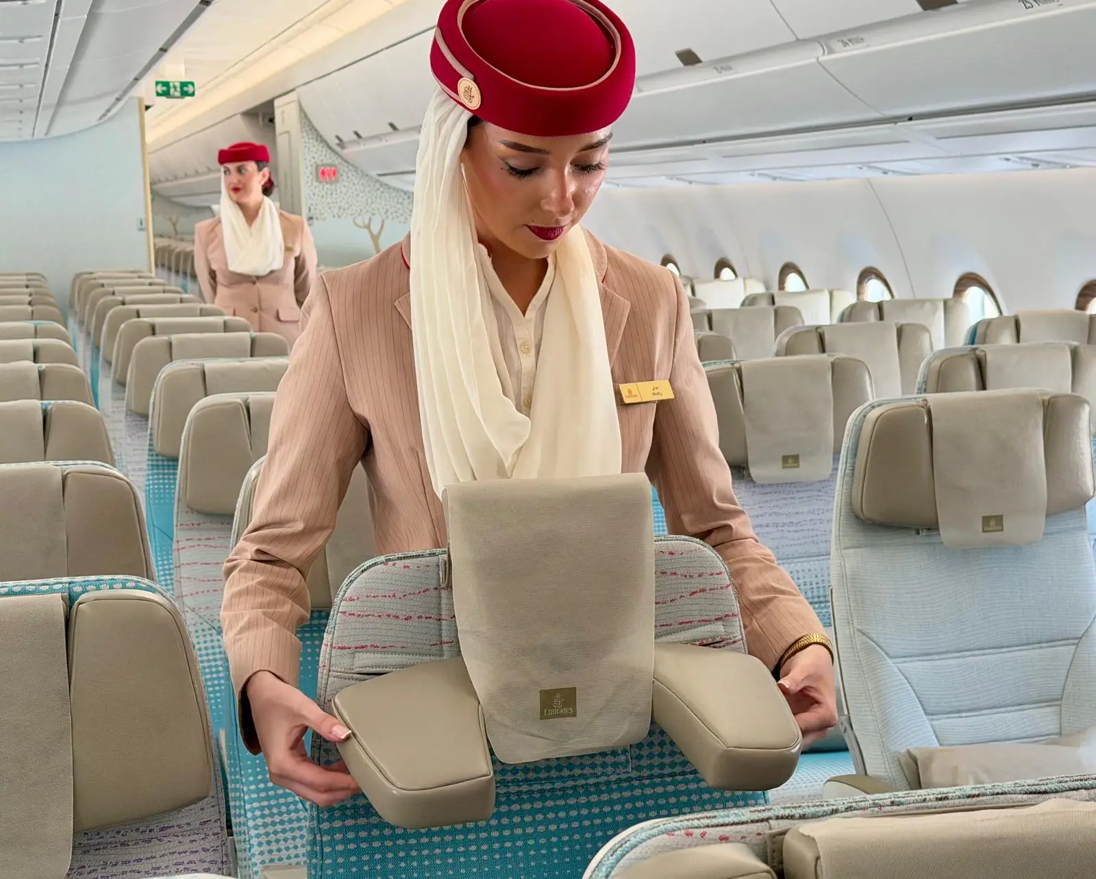 An Emirates flight attendant shows how the new headrest adjusts on an Airbus A350-900 on display at the 2026 Farnborough Airshow