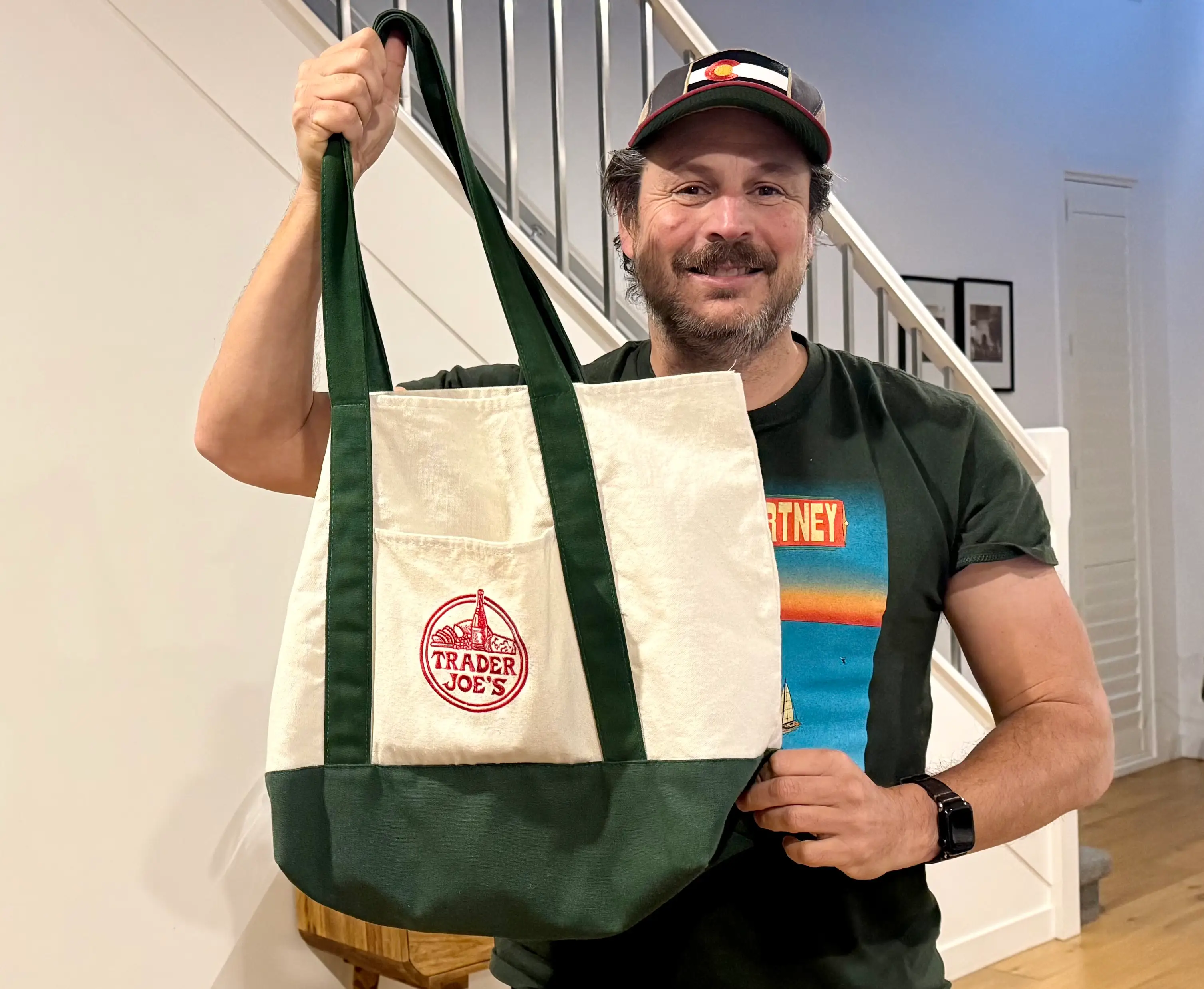 Man smiling, holding Trader Joe's tote bag