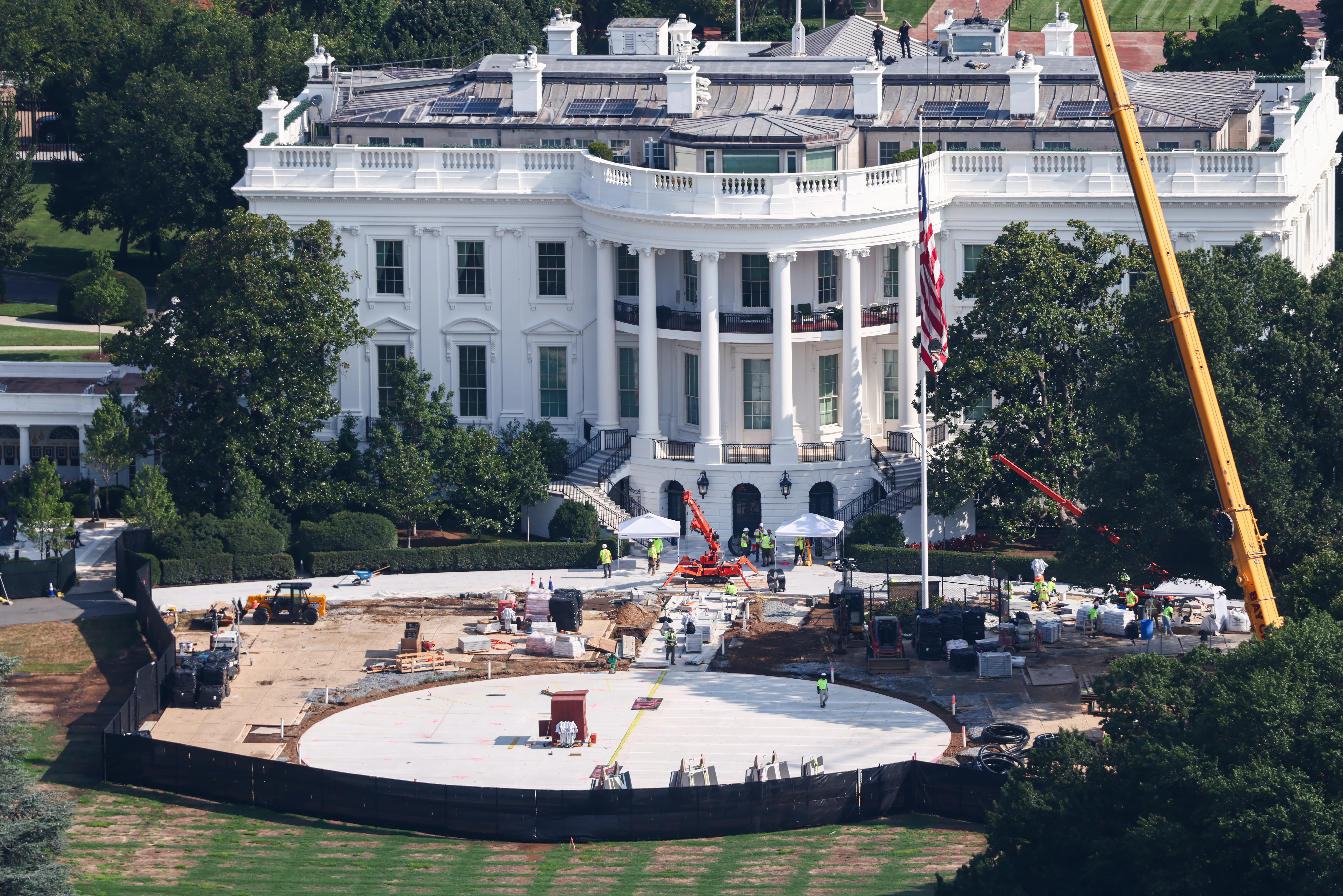 Construction equipment and workers surround a circular work area on the South Lawn in front of the White House.