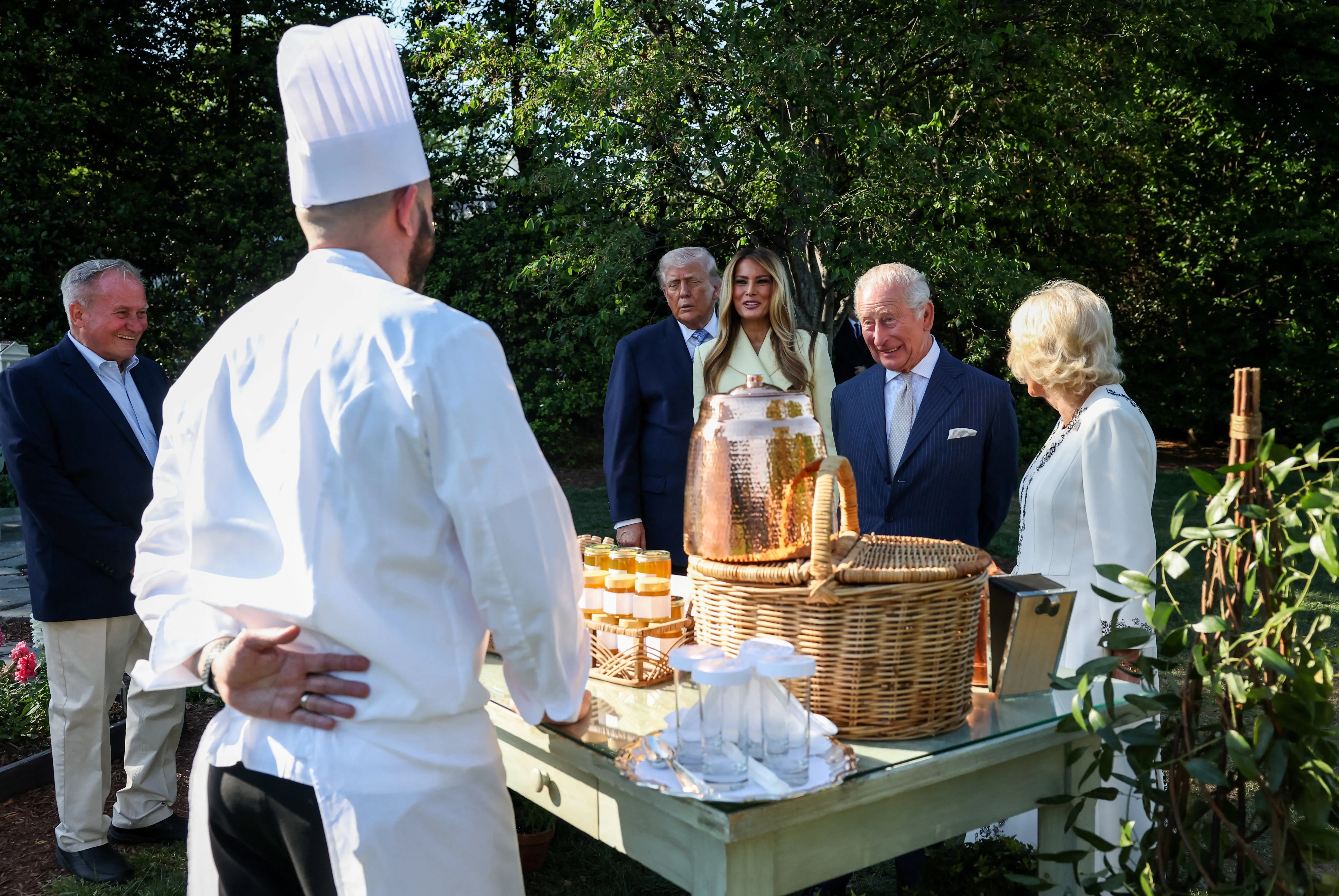 Donald Trump, Melania Trump, King Charles III and Queen Camilla stand beside a chef at an outdoor table.