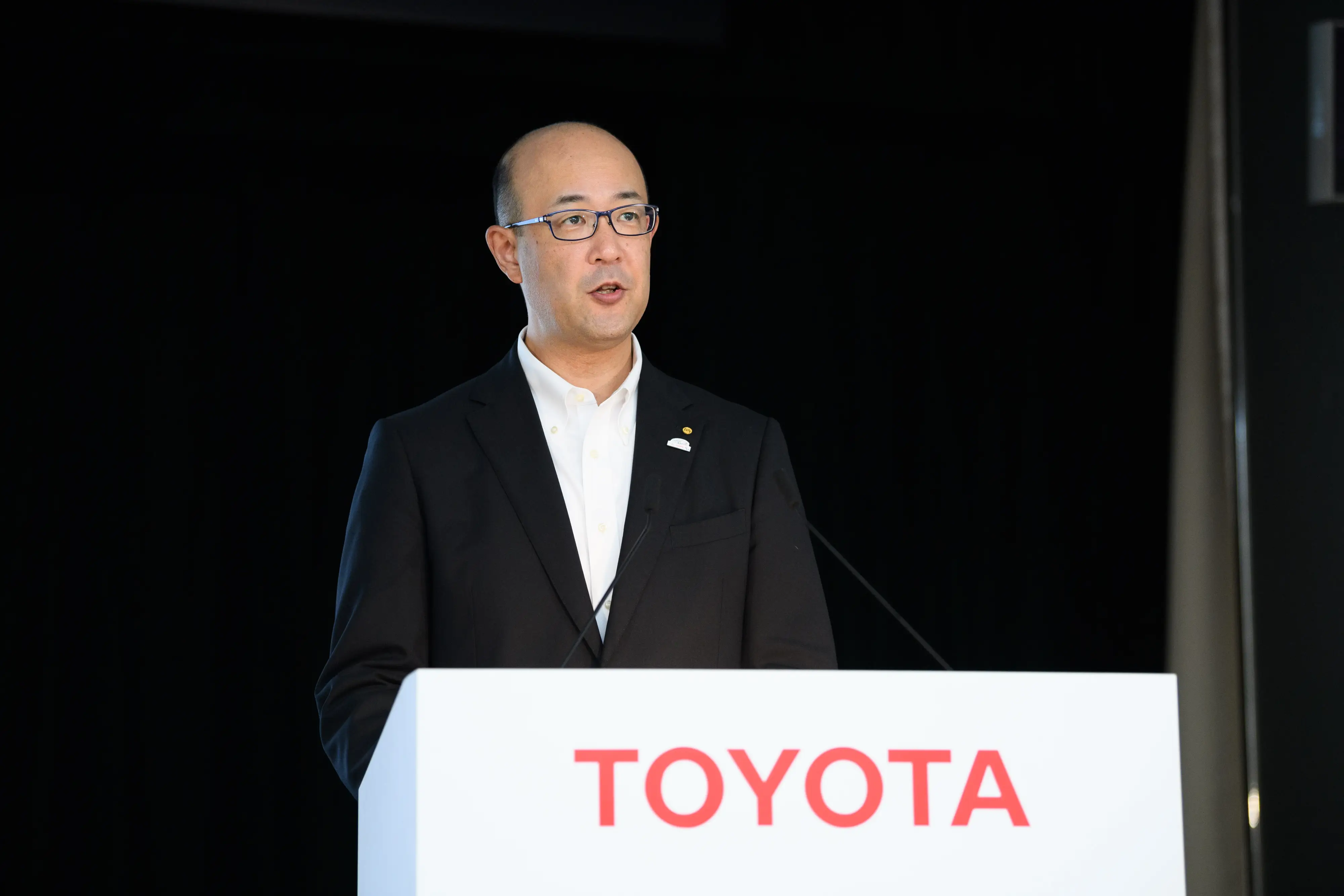 CEO Kenta Kon speaking at a Toyota-branded lectern.