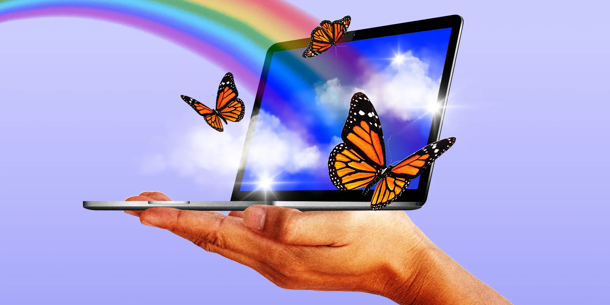A hand holding a laptop displaying rainbows and butterflies