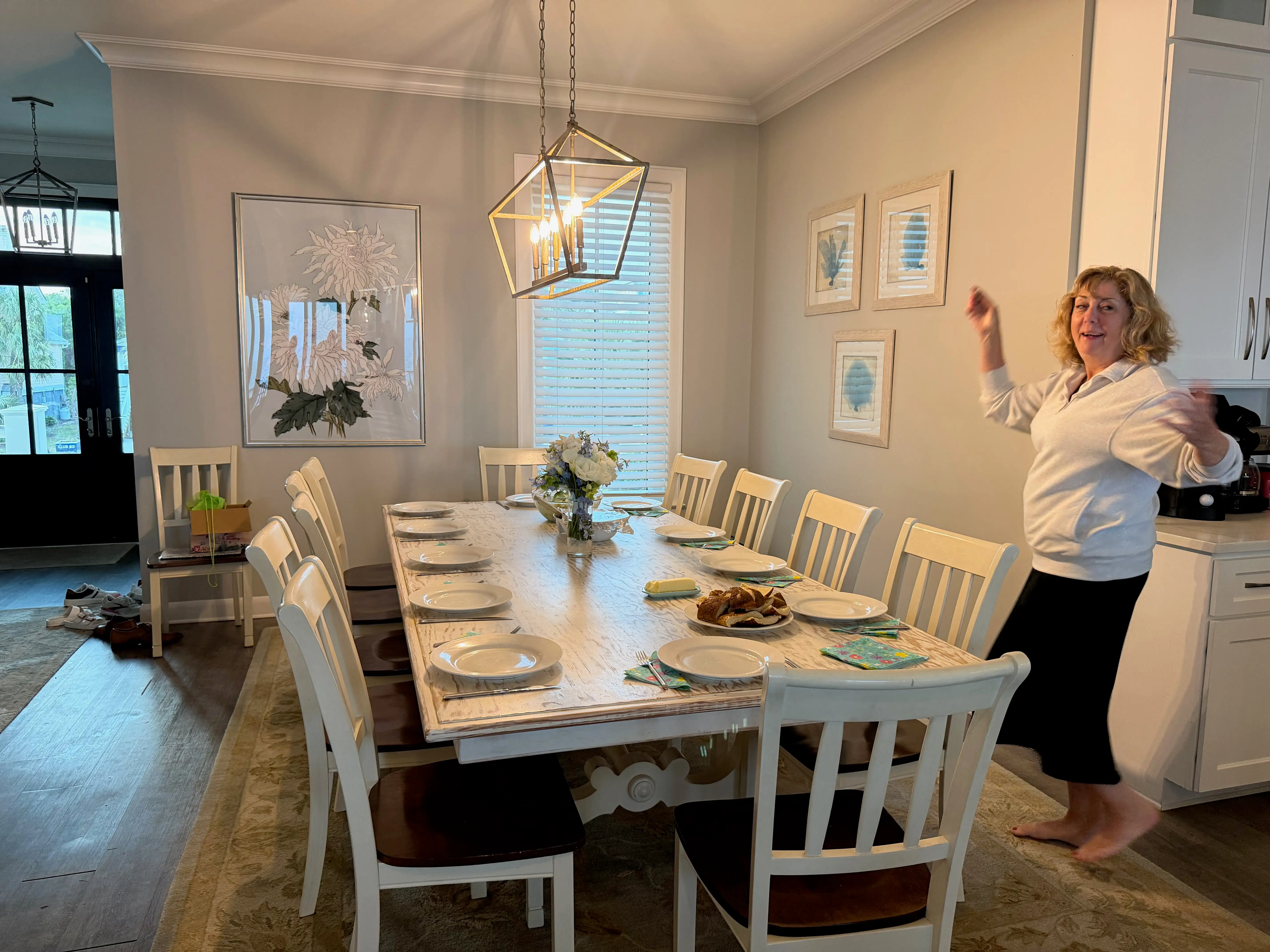 A woman dances in a mostly white dining room.