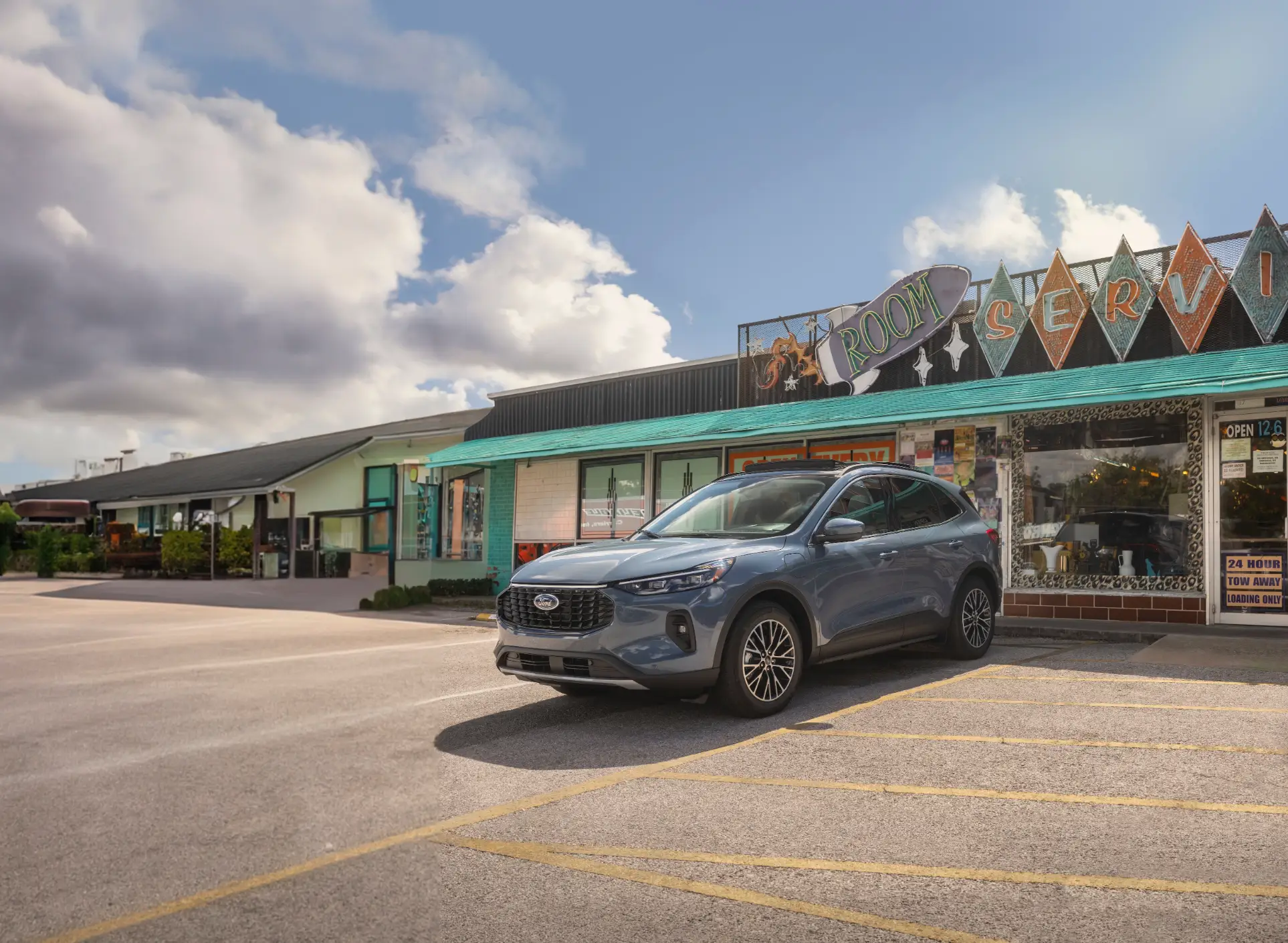 A blue Ford Escape is parked in front of a motel.