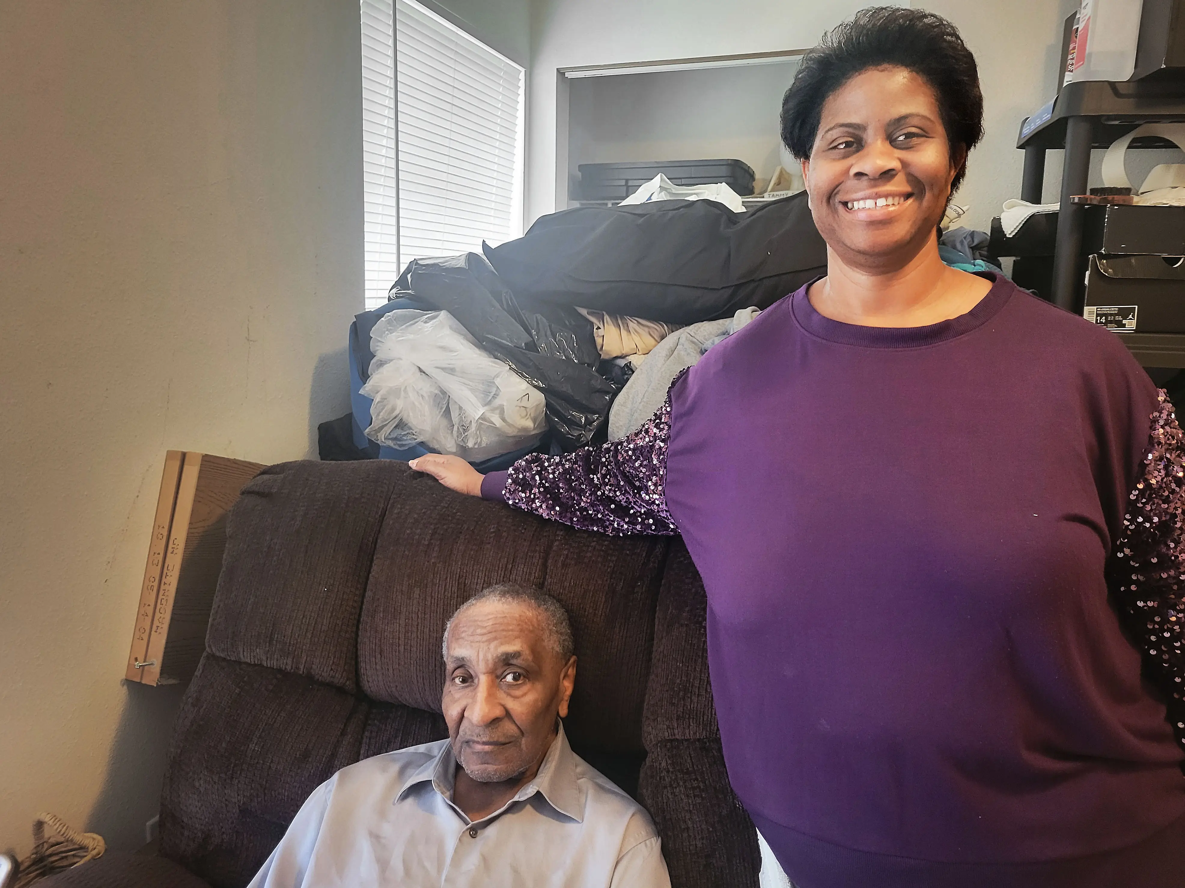 Tammy Shanklin stands next to her grandfather, who is sitting in a chair