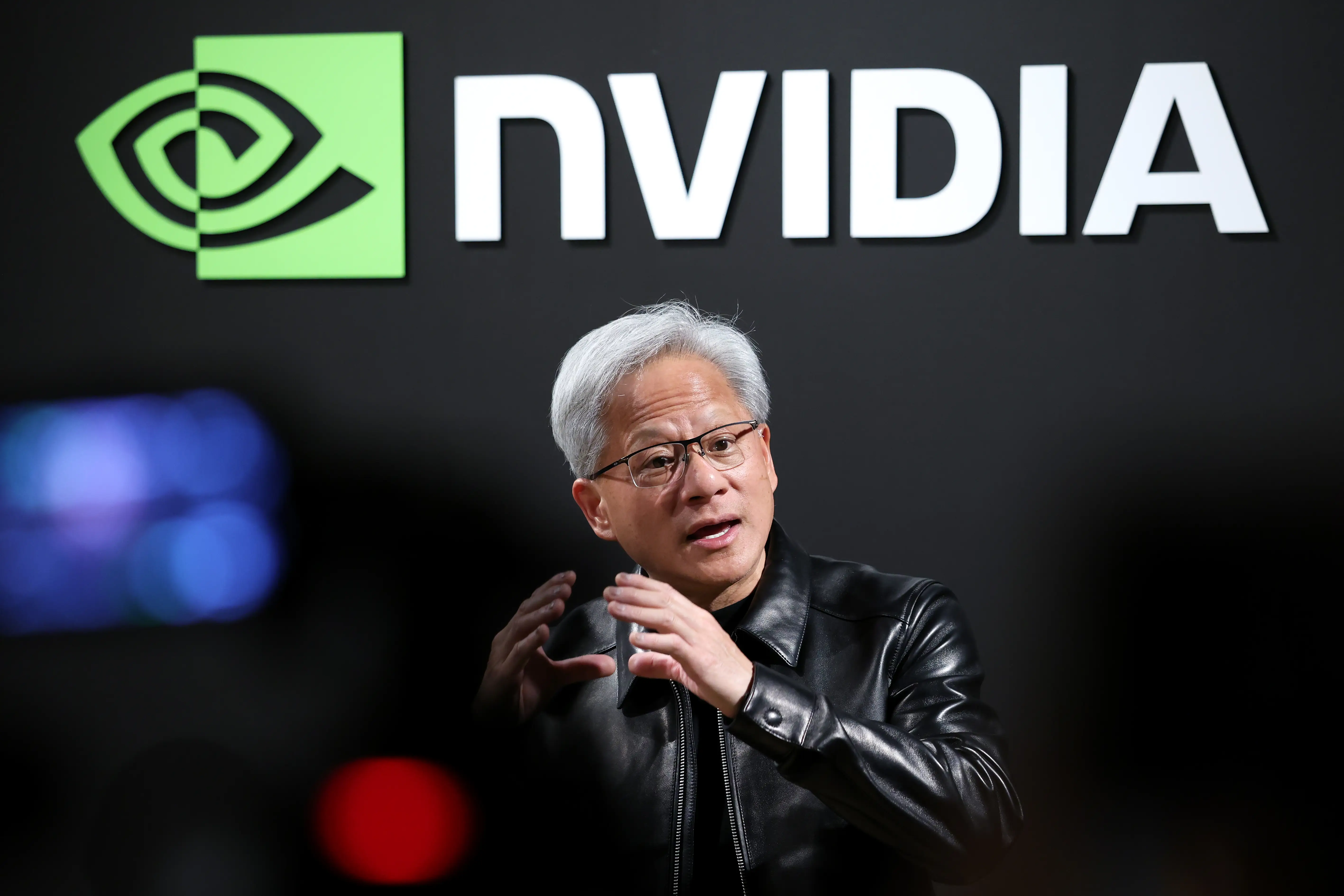 Jensen Huang stands in front of an NVIDIA sign